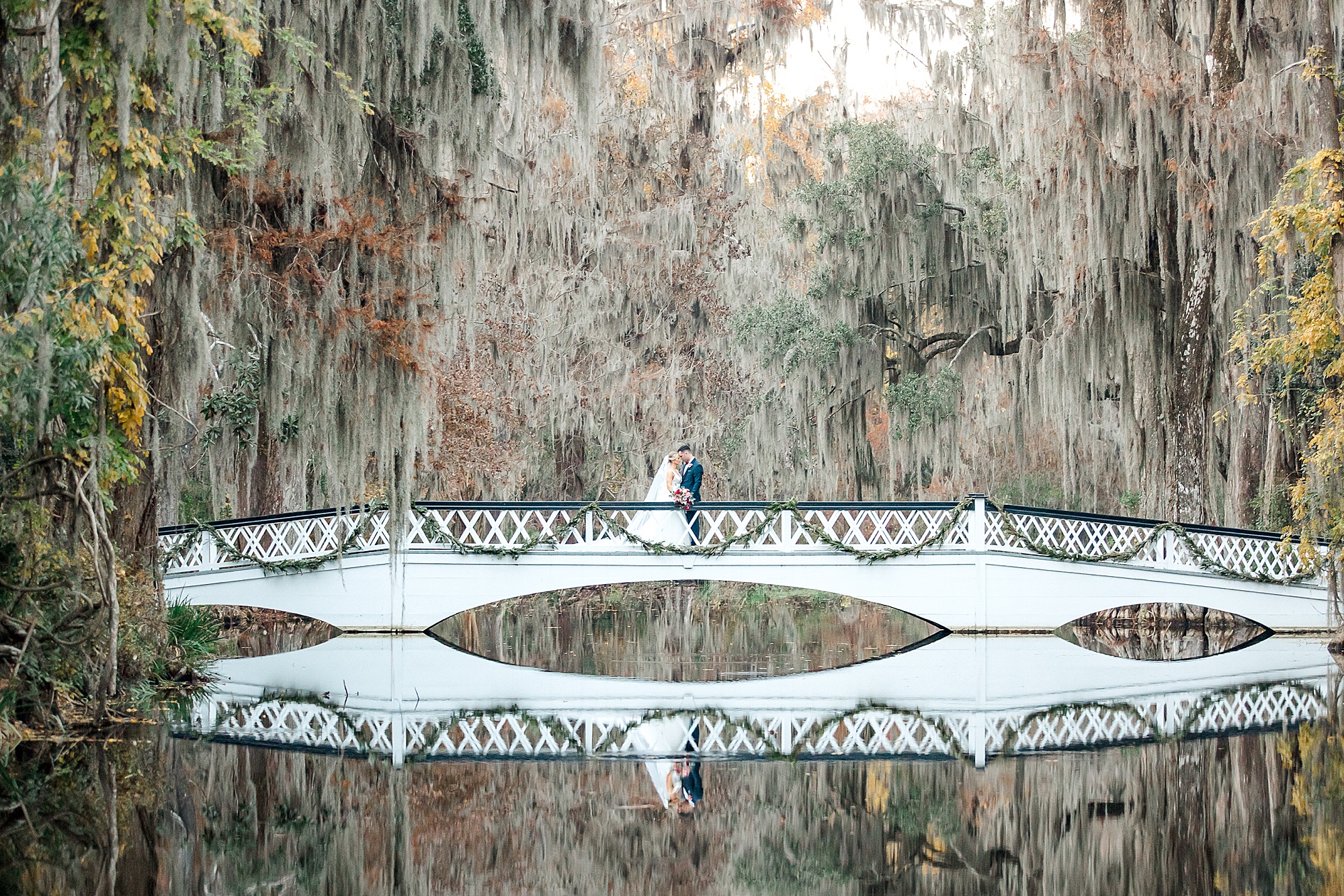 couple on bridge with spanish moss covered trees overhead