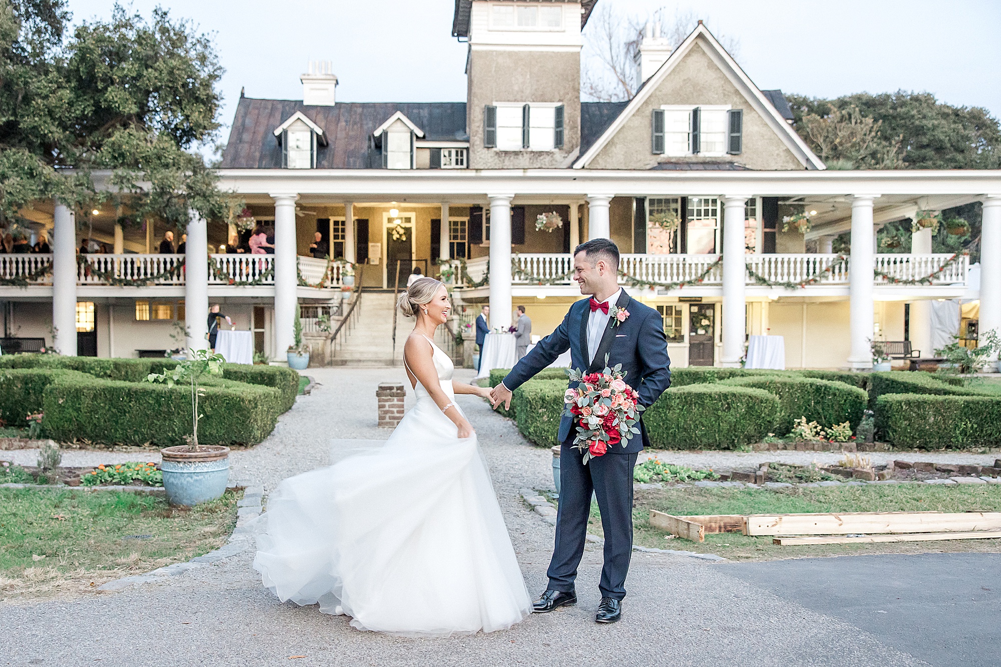couple walk in the front of the stunning Magnolia Plantation in Charleston SC