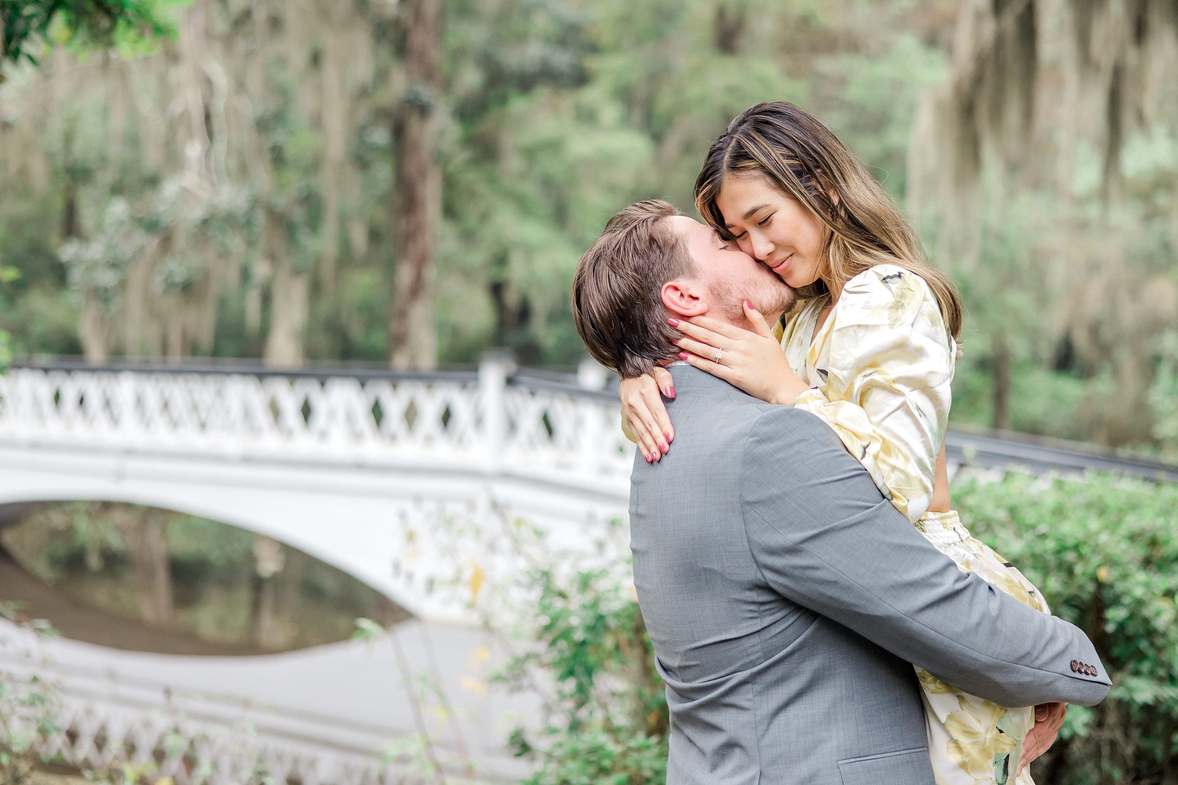 Couple kisses in front of white bridge at Magnolia Plantation and Gardens