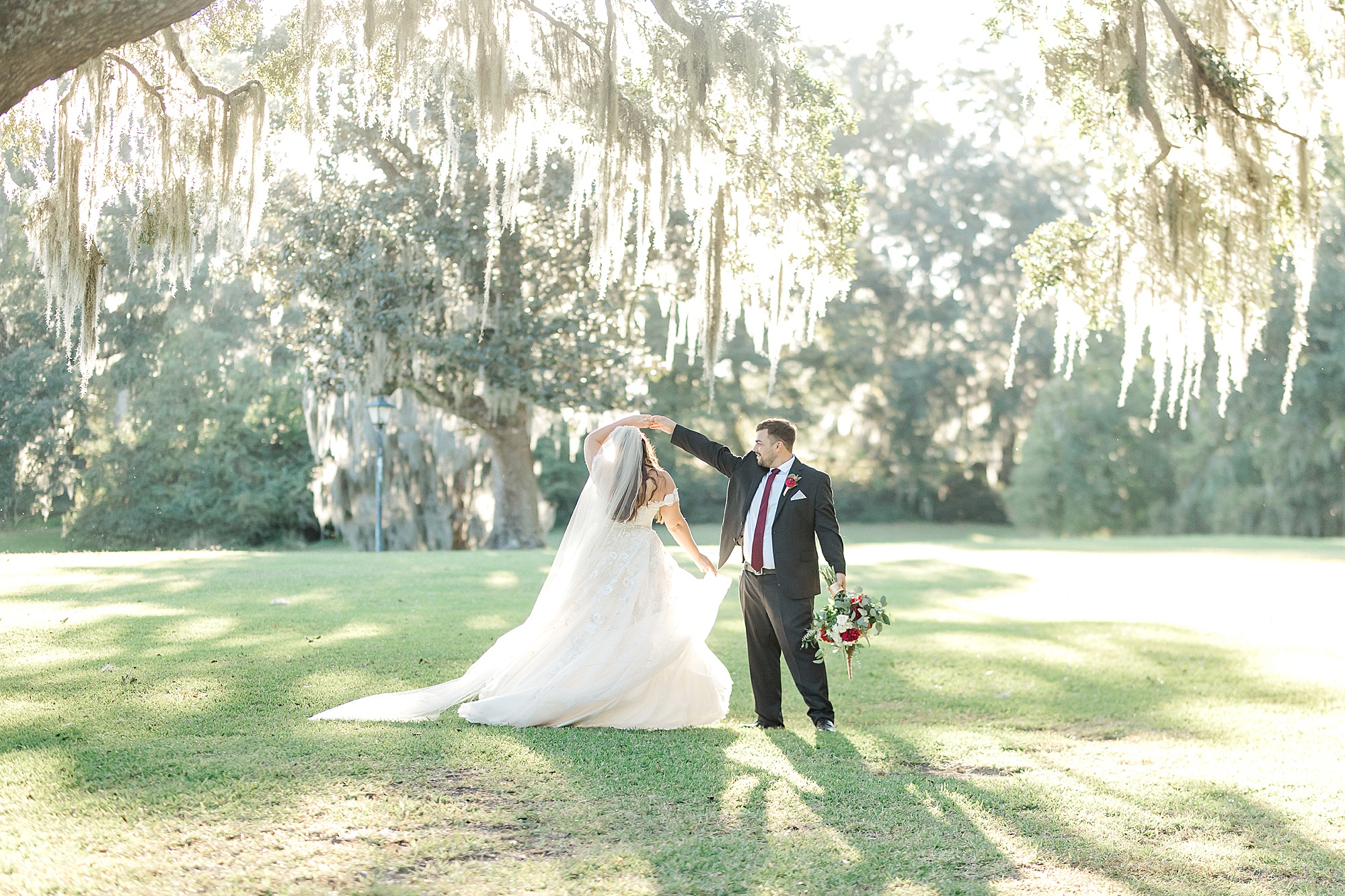 newlyweds dance in the grass under oak trees in Charleston SC