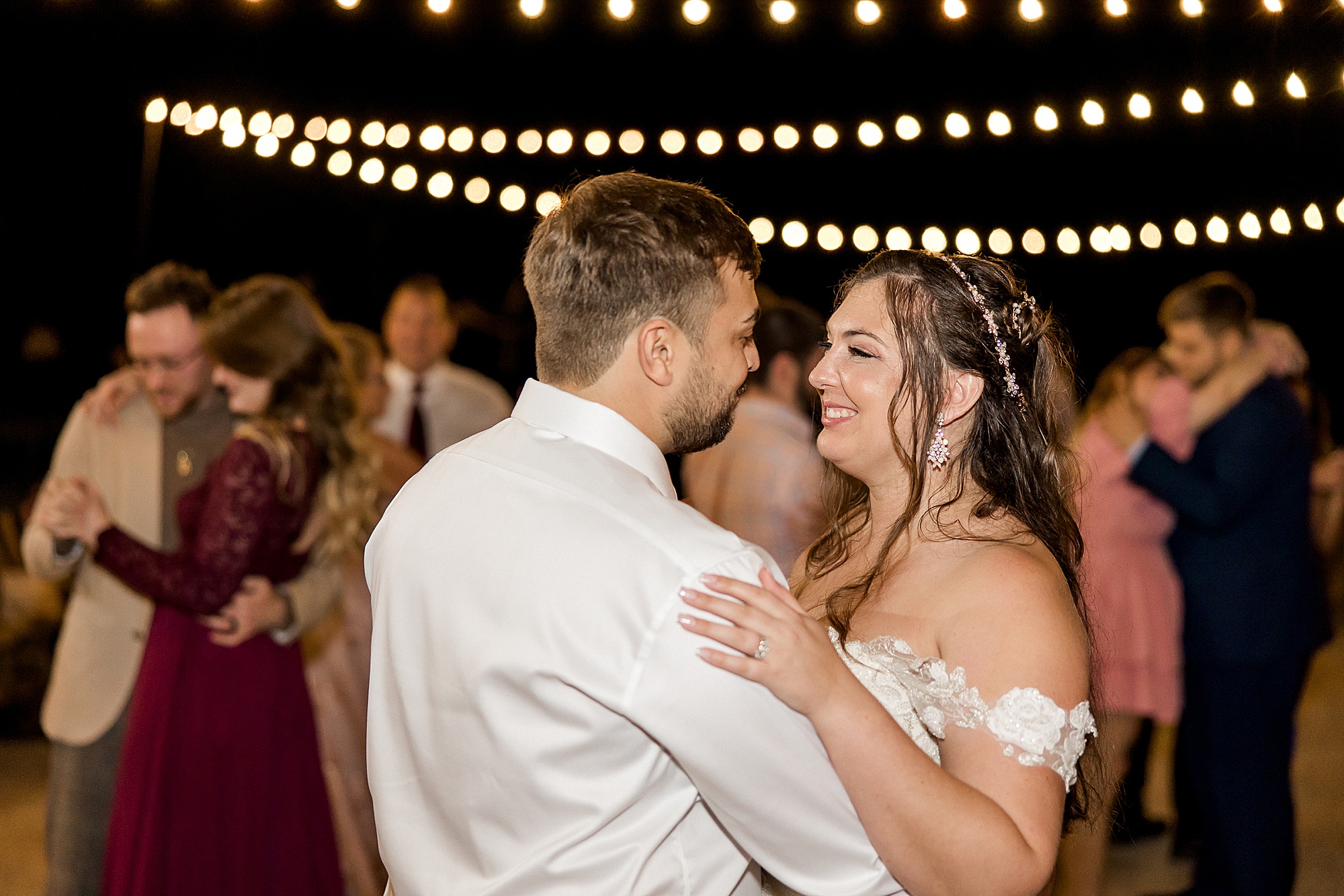 bride and groom dancing under stringed lights