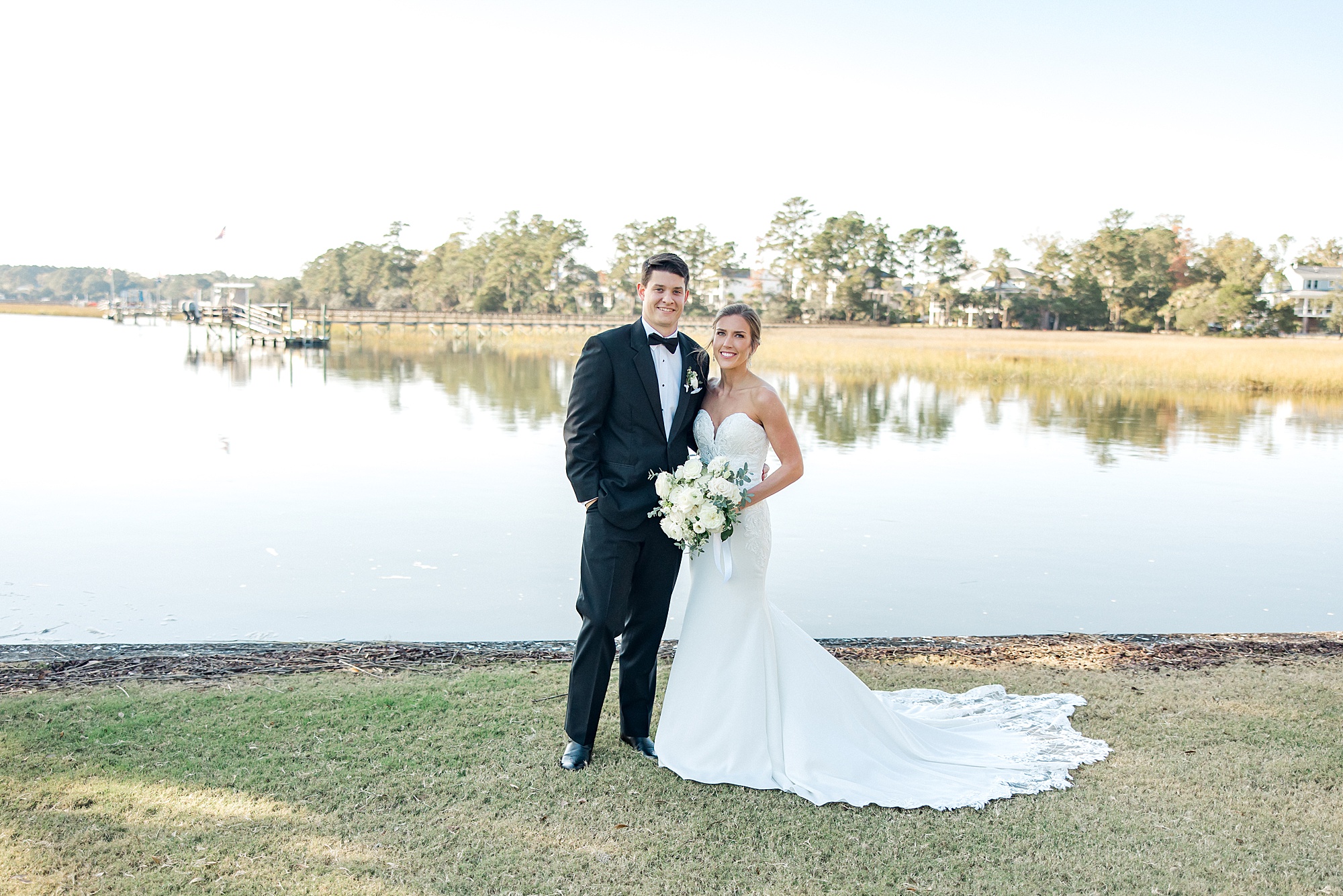 bride and groom stand by beautiful lake in SC at Dunes West Golf and River Club