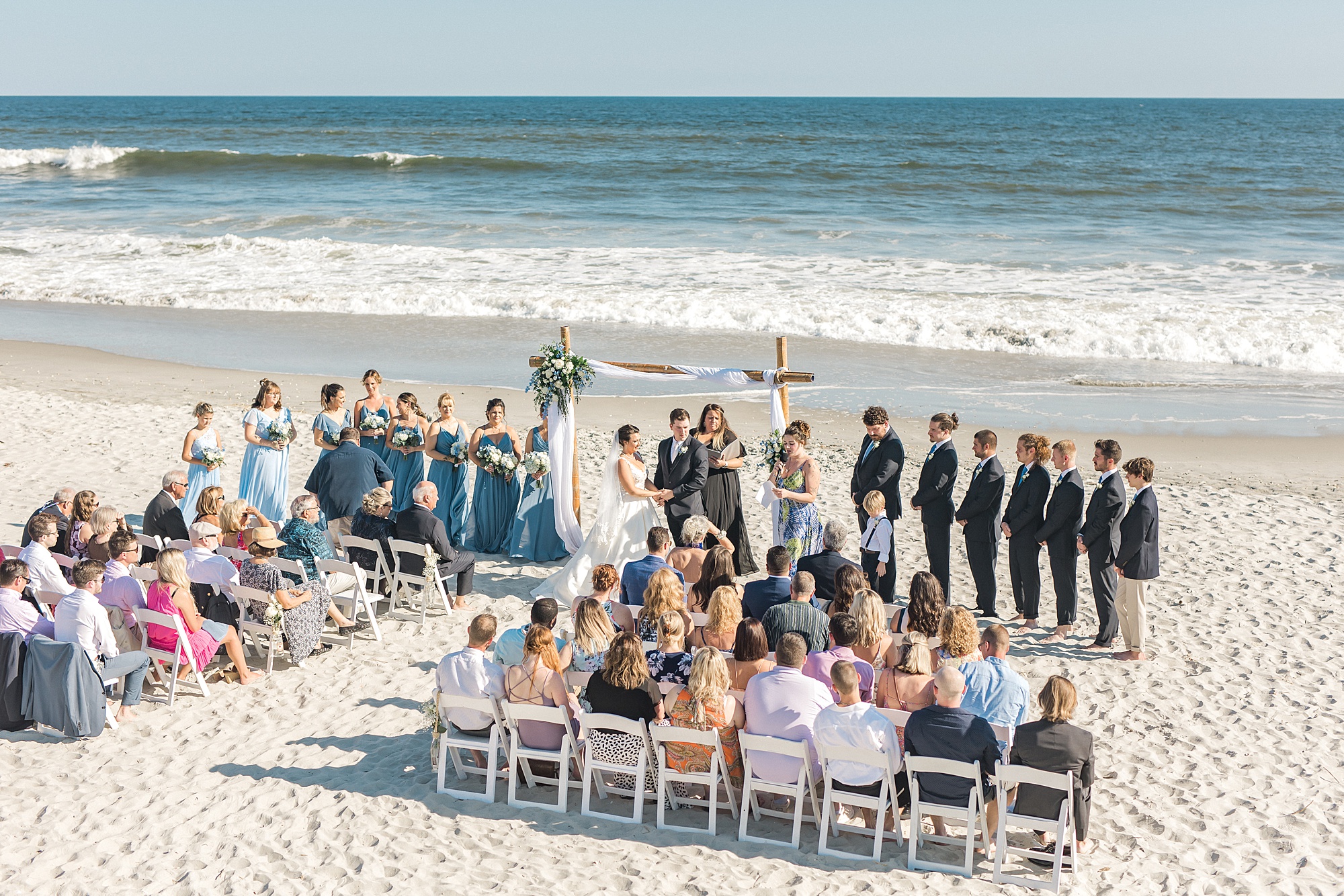 guests gather on the beach to watch seaside wedding