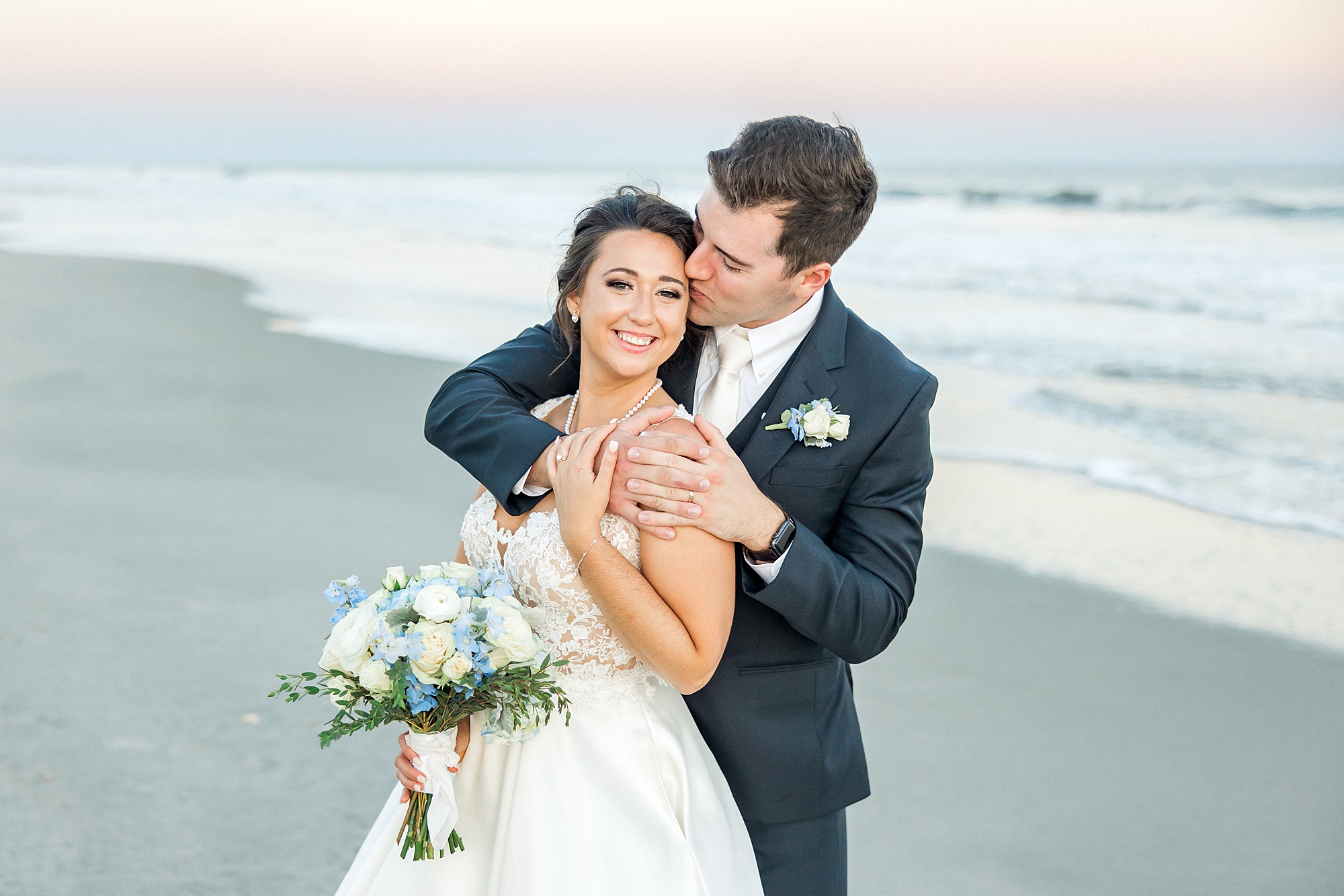 husband kisses his new bride on the beach