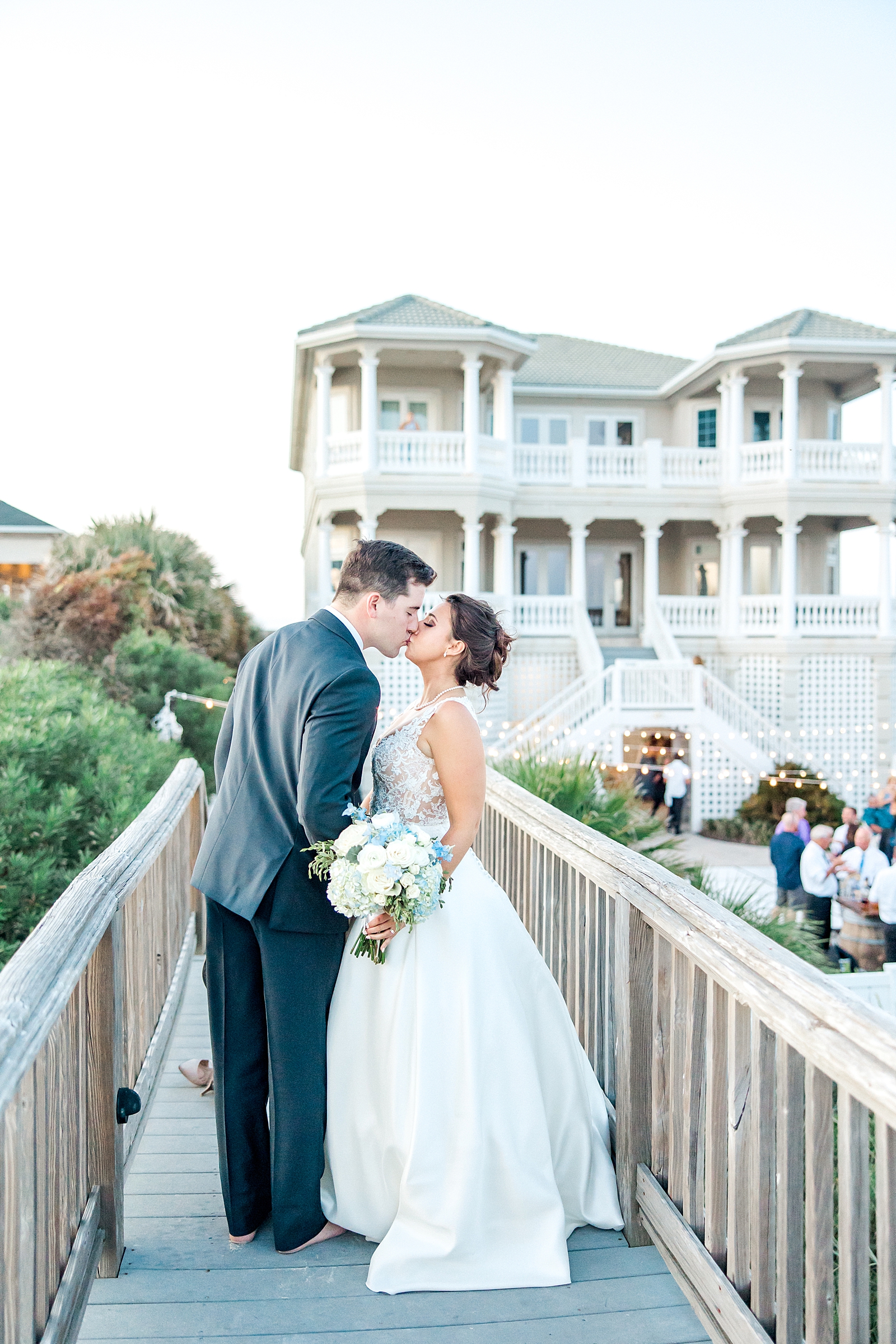 newlyweds kiss with the beach house in the background