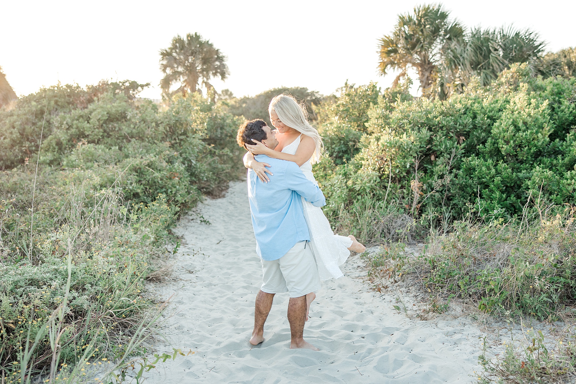 man lifts his fiance up during Folly Beach Engagement Session