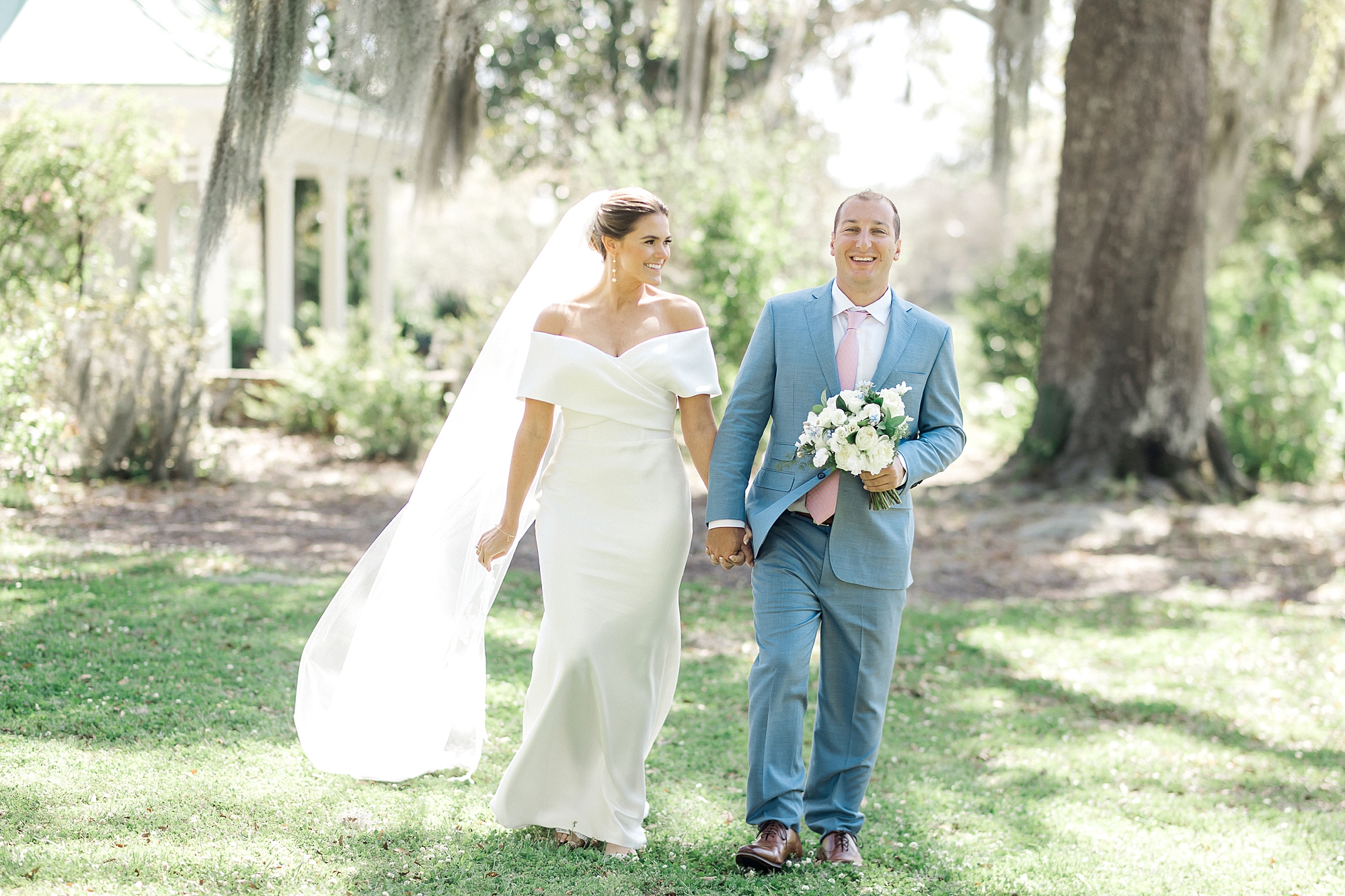 couple walking and holding hands under Oak trees at the William Aiken House
