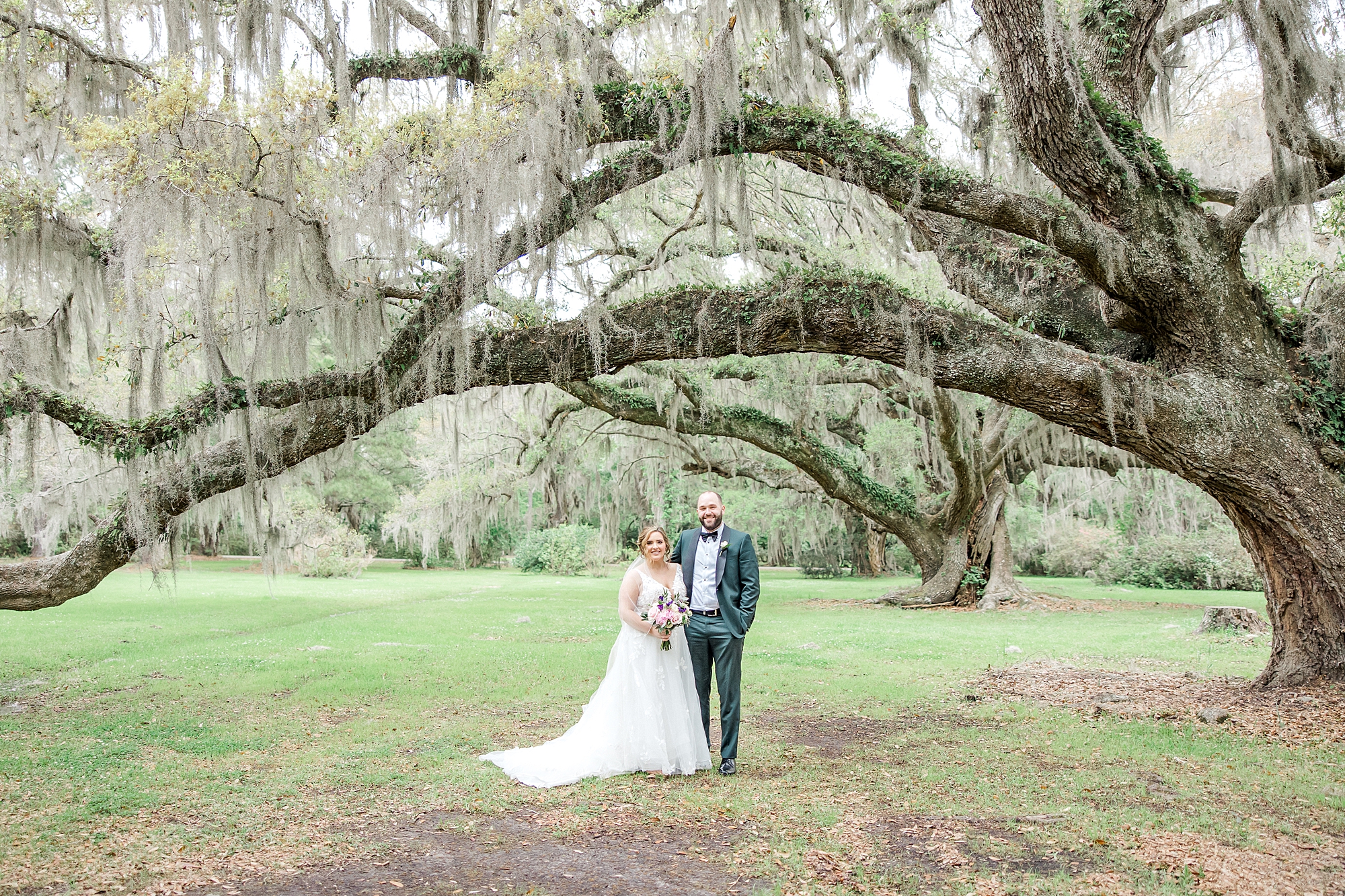 couple stand under oak tree covered in spanish moss
