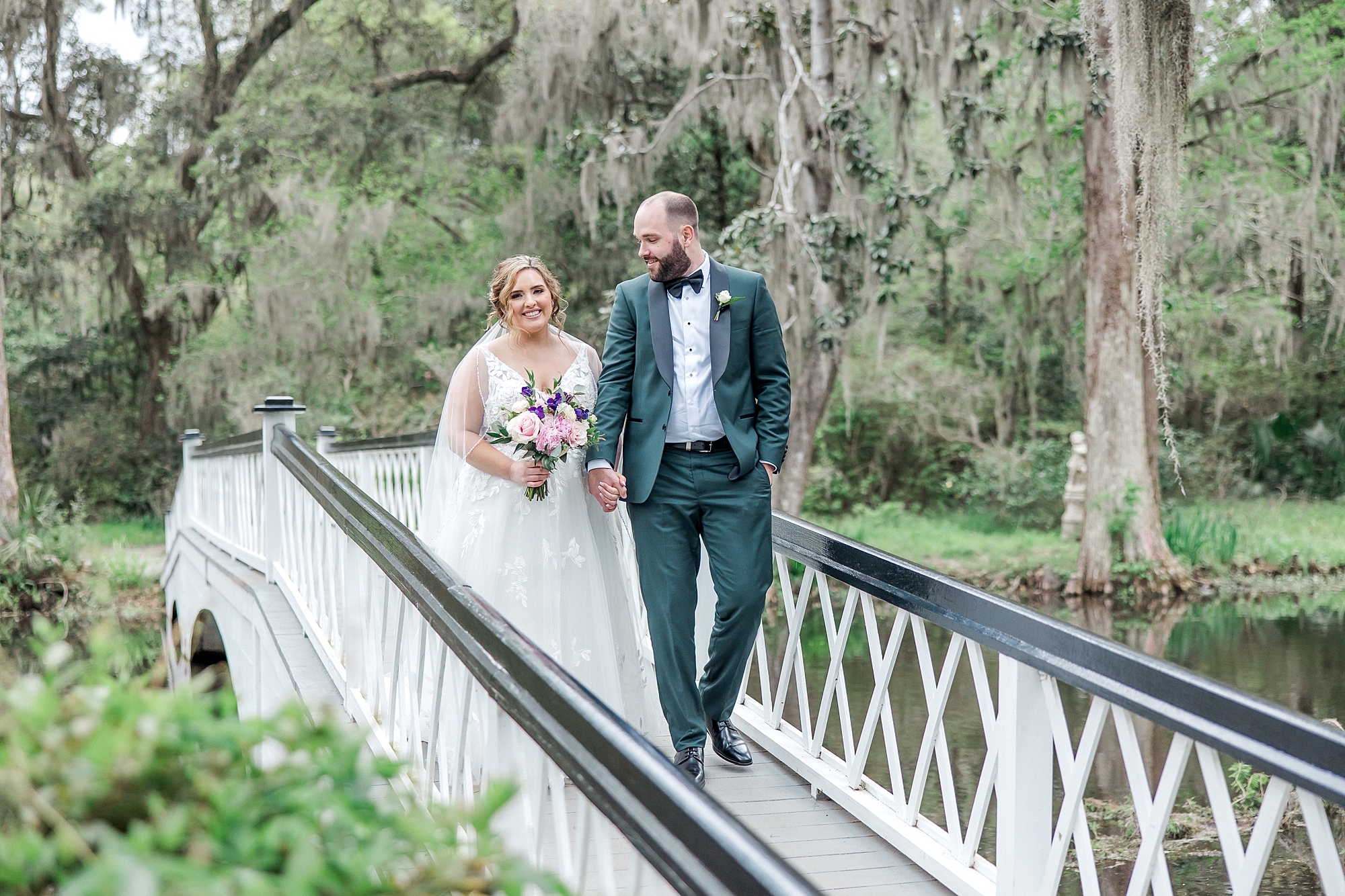 newlyweds hold hands walking across bridge
