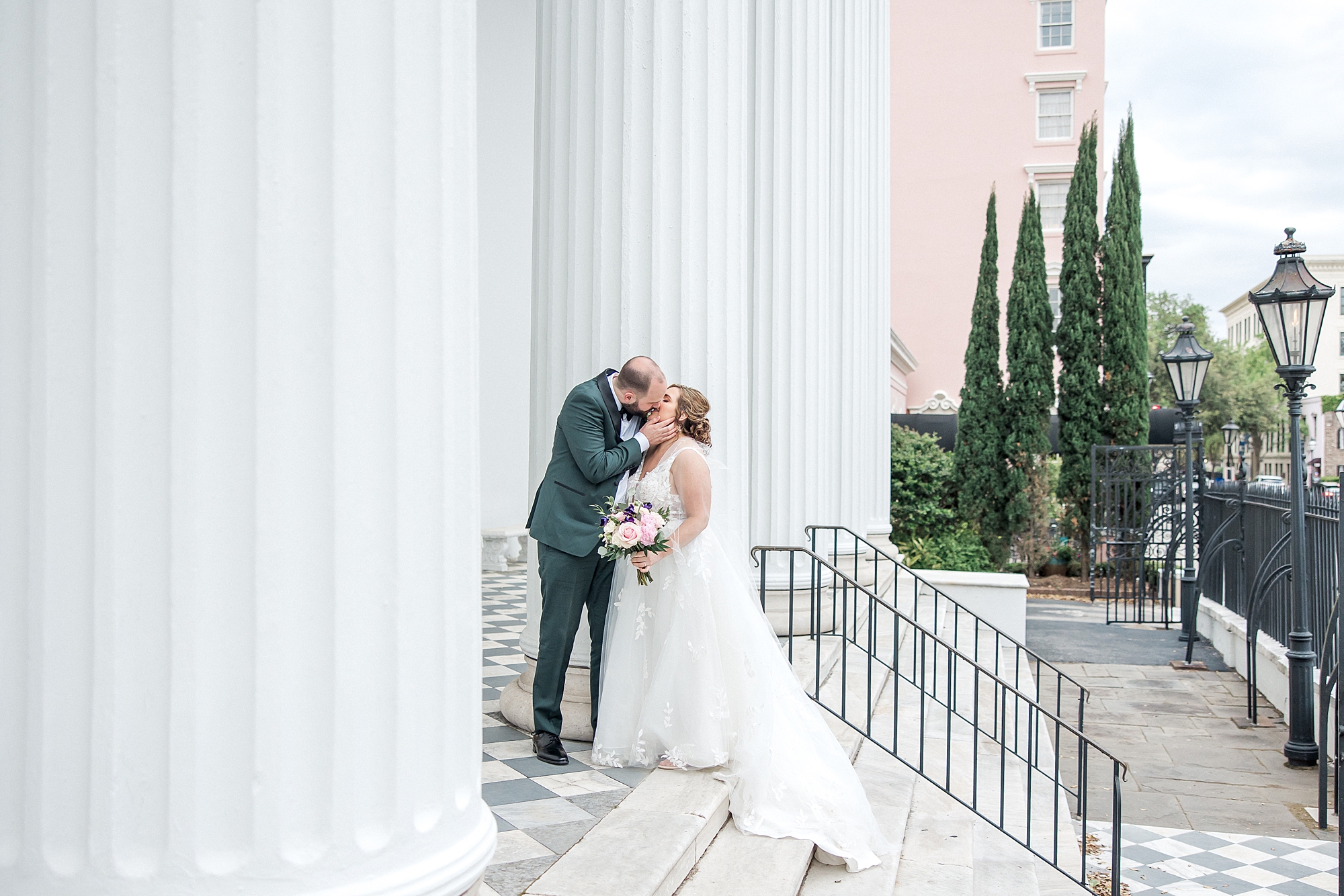 husband kisses bride as they stand on steps