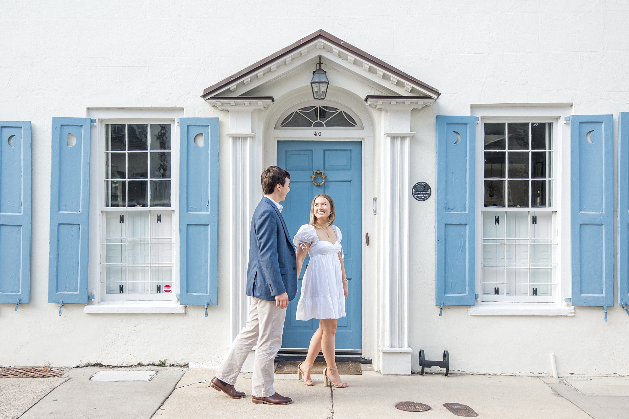 couple in front of iconic white and blue house in Charleston SC