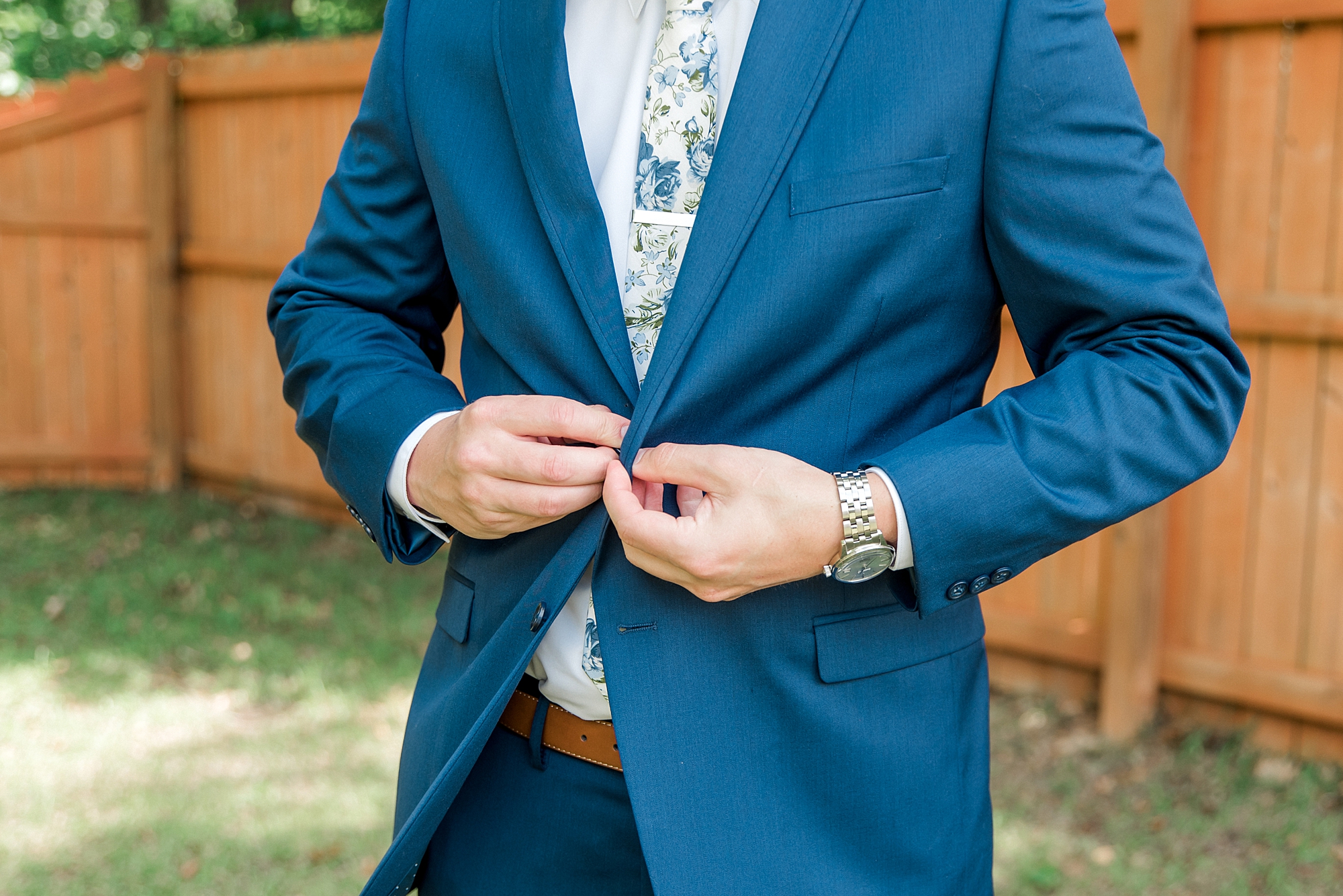 groom buttoning up his suit jacket
