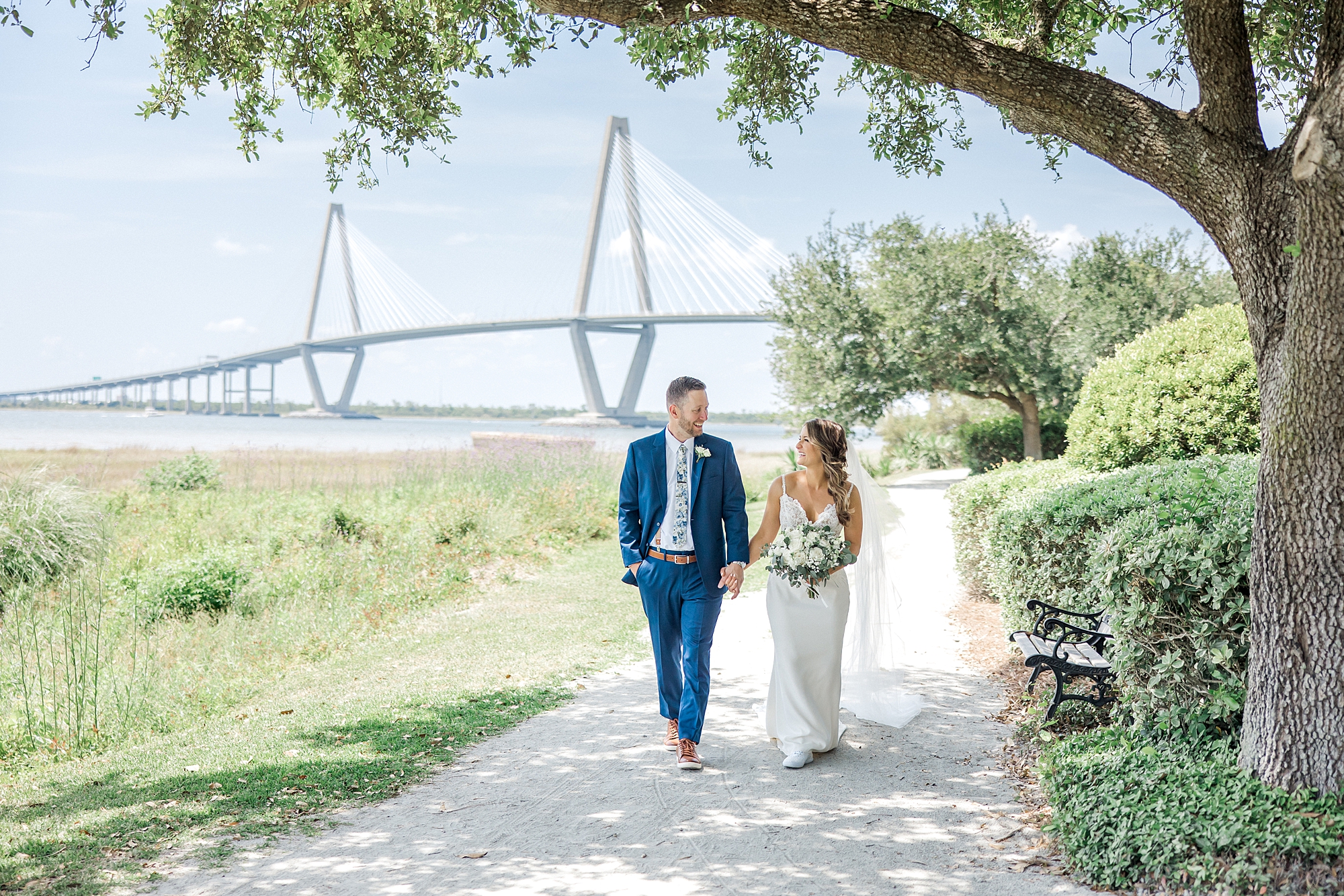 couple walk together with SC bridge in background