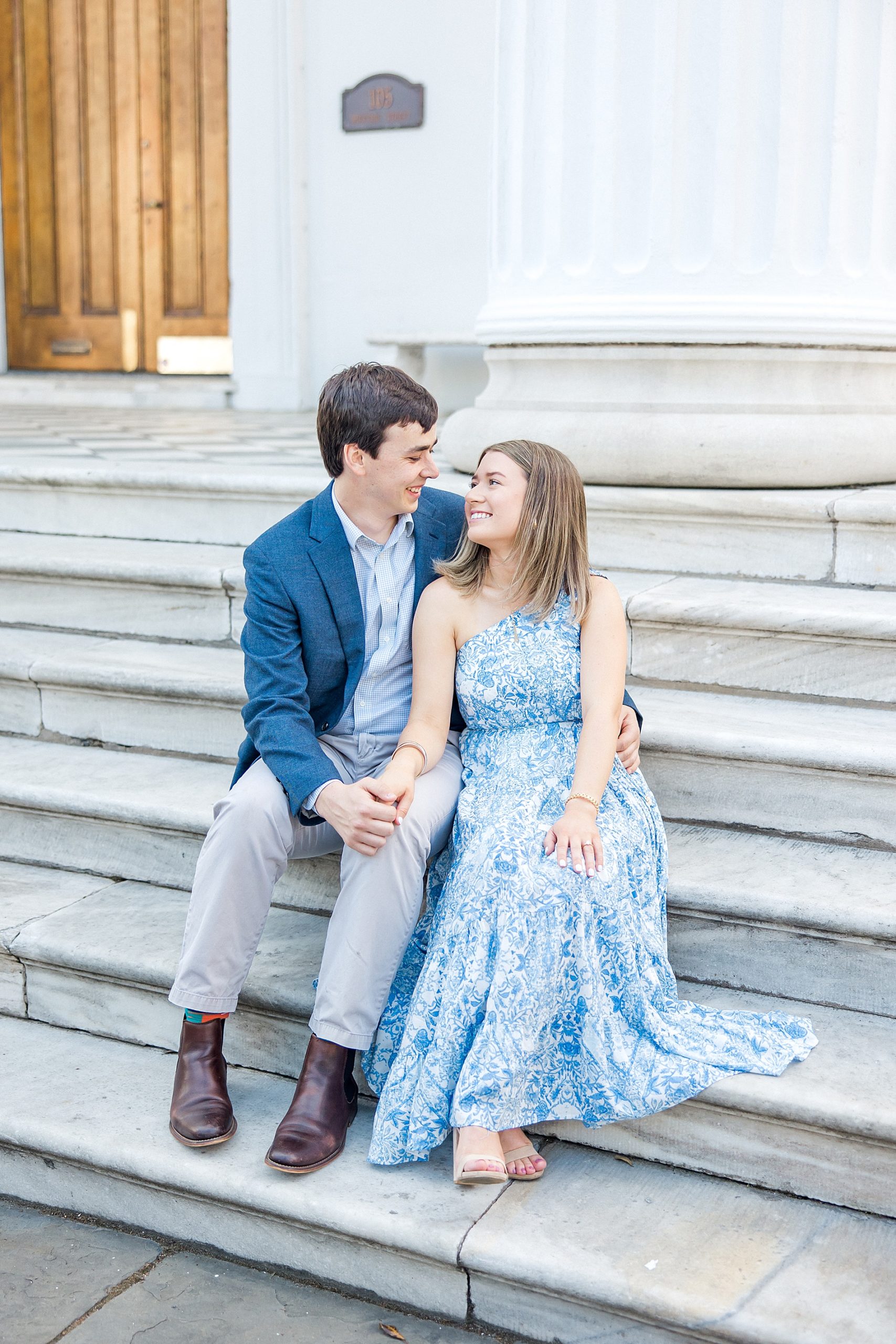 couple sit on stairs of building for engagement portraits
