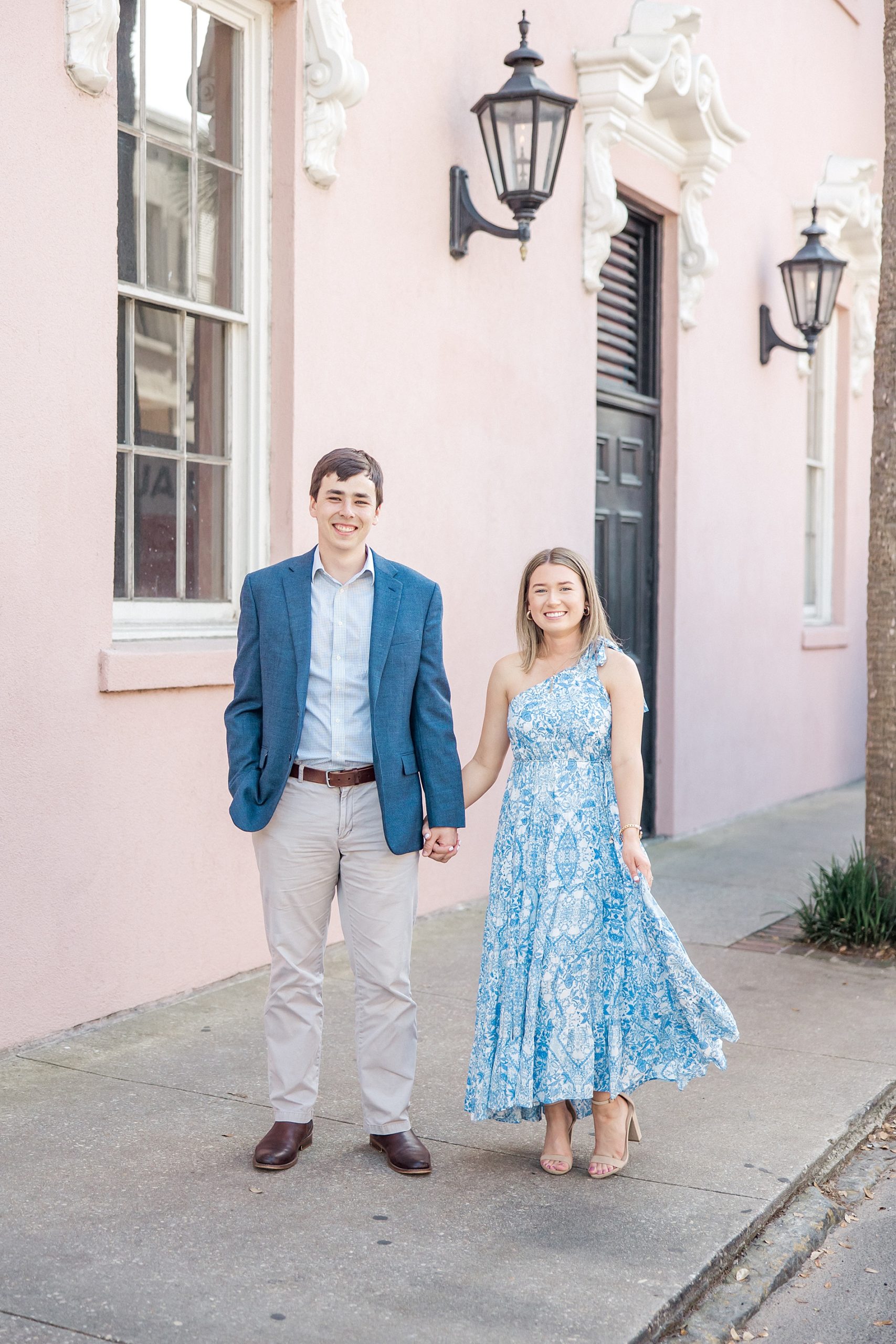 couple walk by iconic pink house in Charleston SC