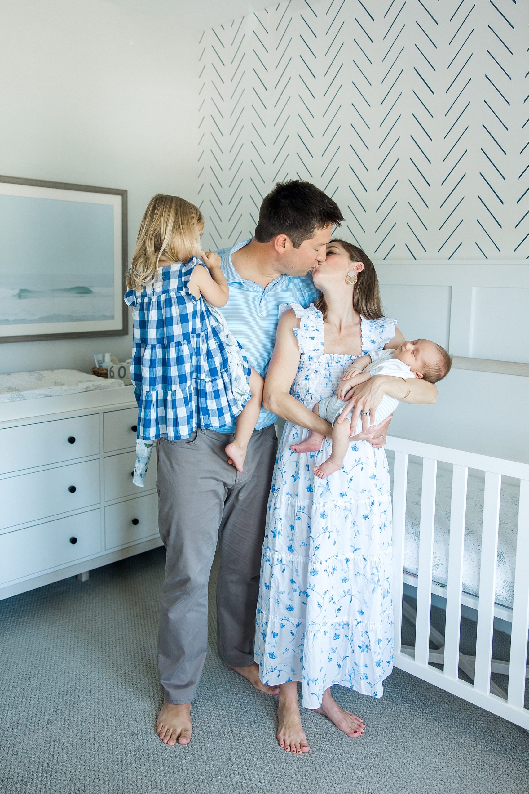 parents kiss while holding their two kids