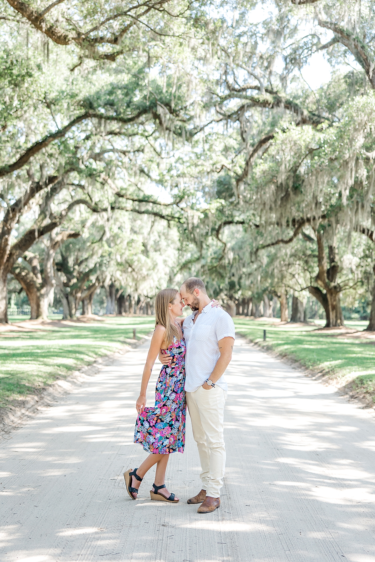 couple kiss under the spanish moss covered oak tress