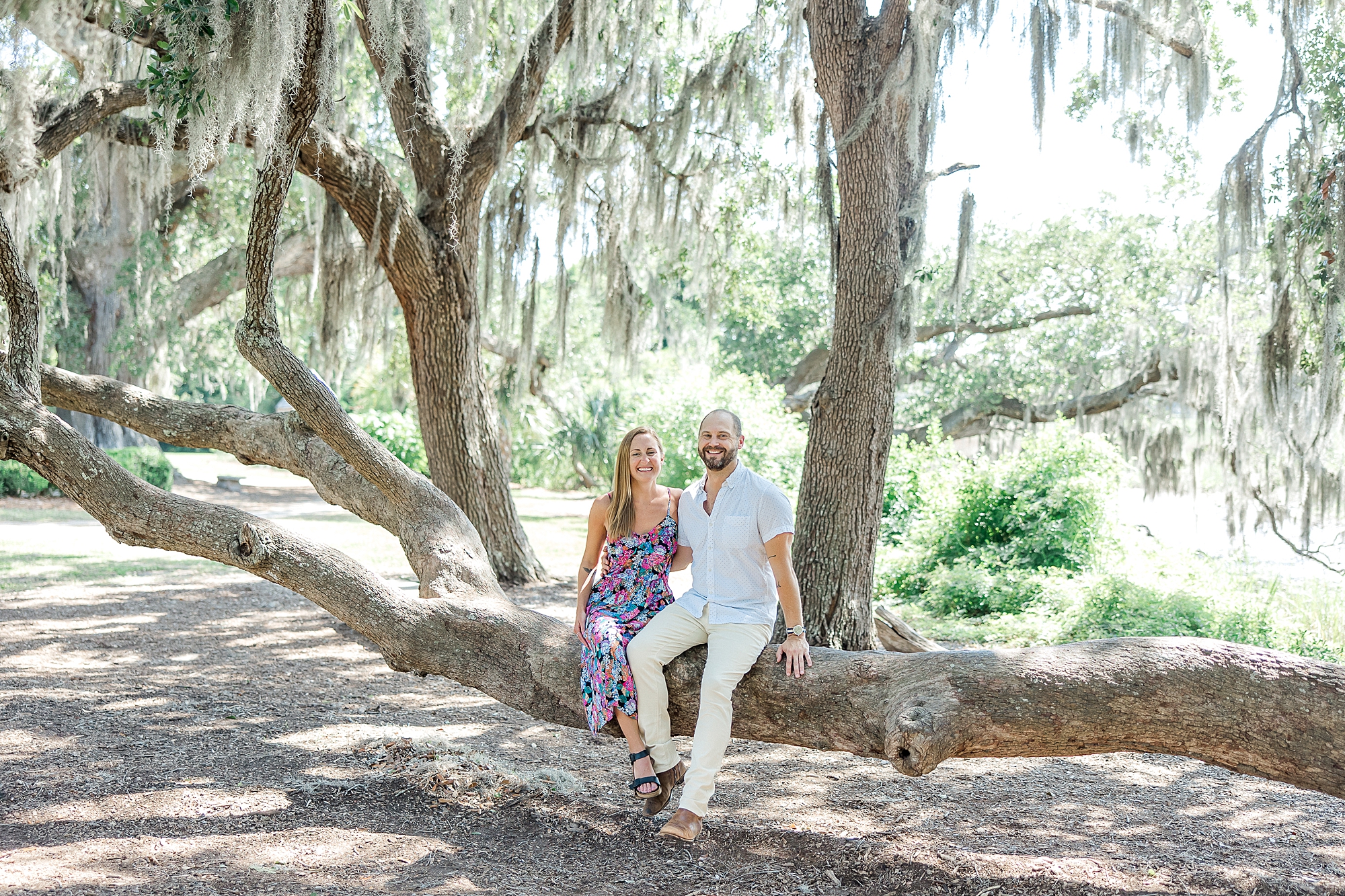 couple sit on low laying oak tree branch during Nature inspired Charleston Engagement