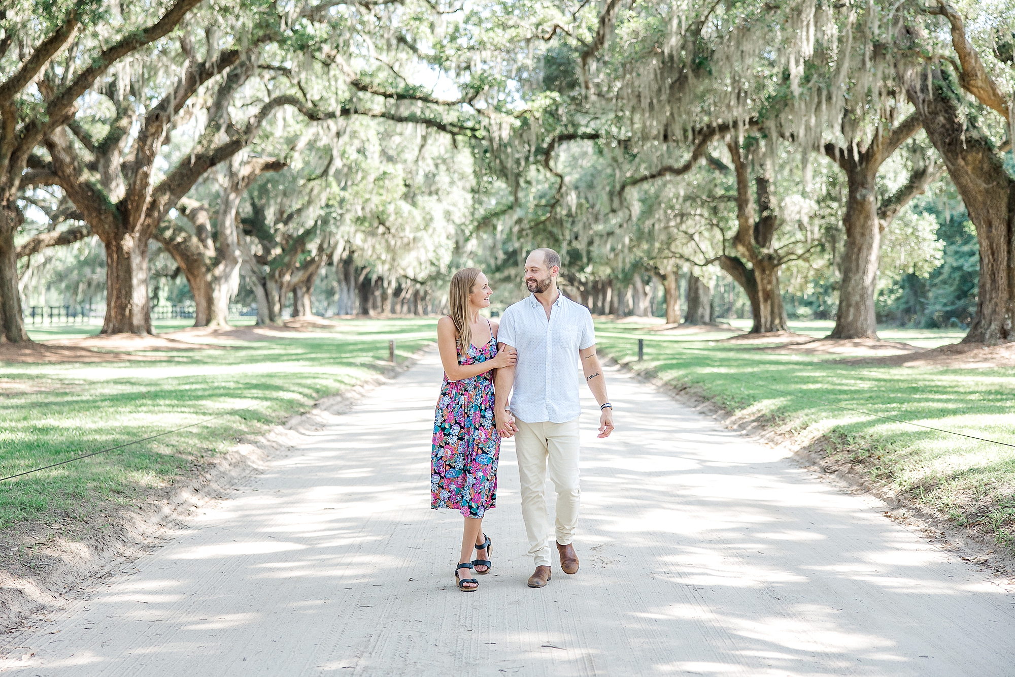 engaged couple walk down Oak Avenue at Boone Hall Plantation in Charleston