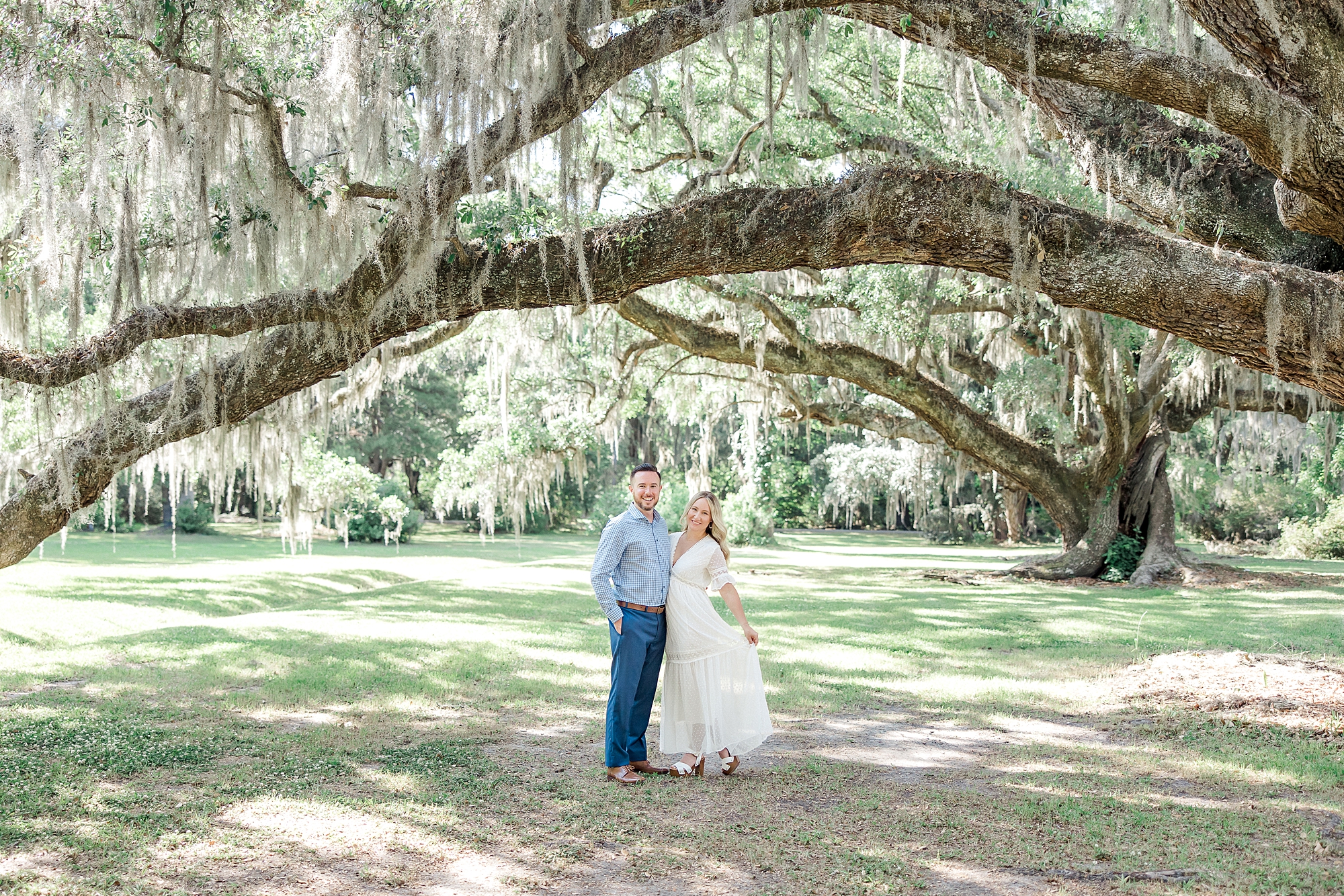 couple under live oak trees in Charleston during engagement portraits