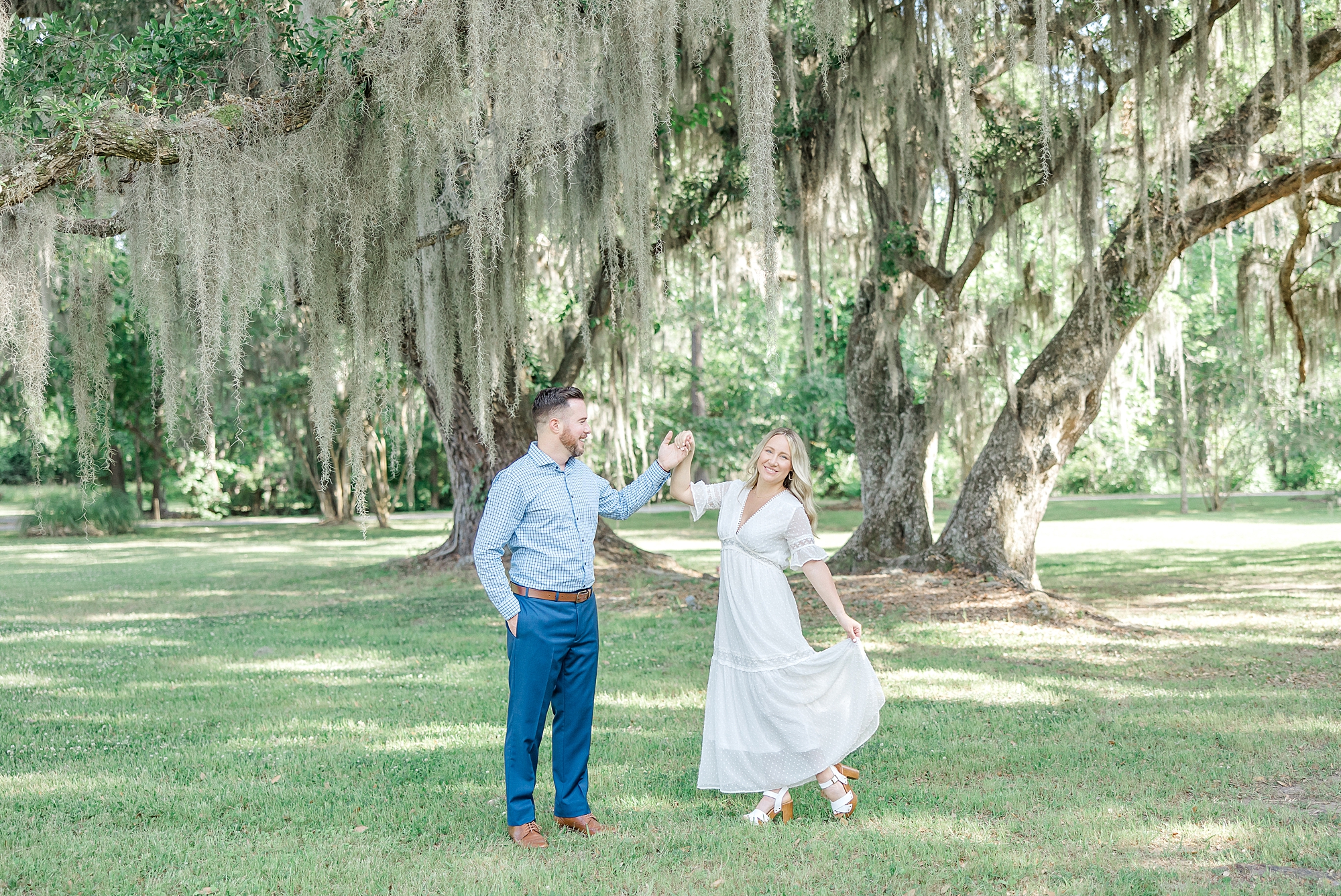 engaged couple dance under the Spanish moss covered trees
