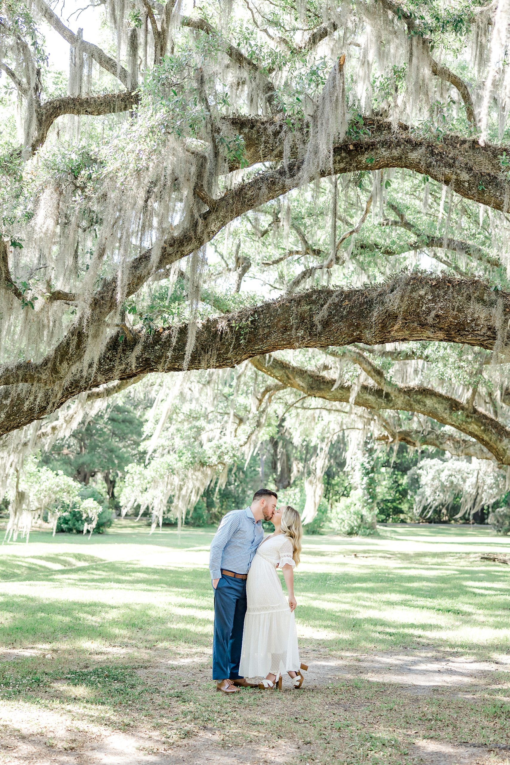 engaged couple kiss under iconic trees during Charleston engagement