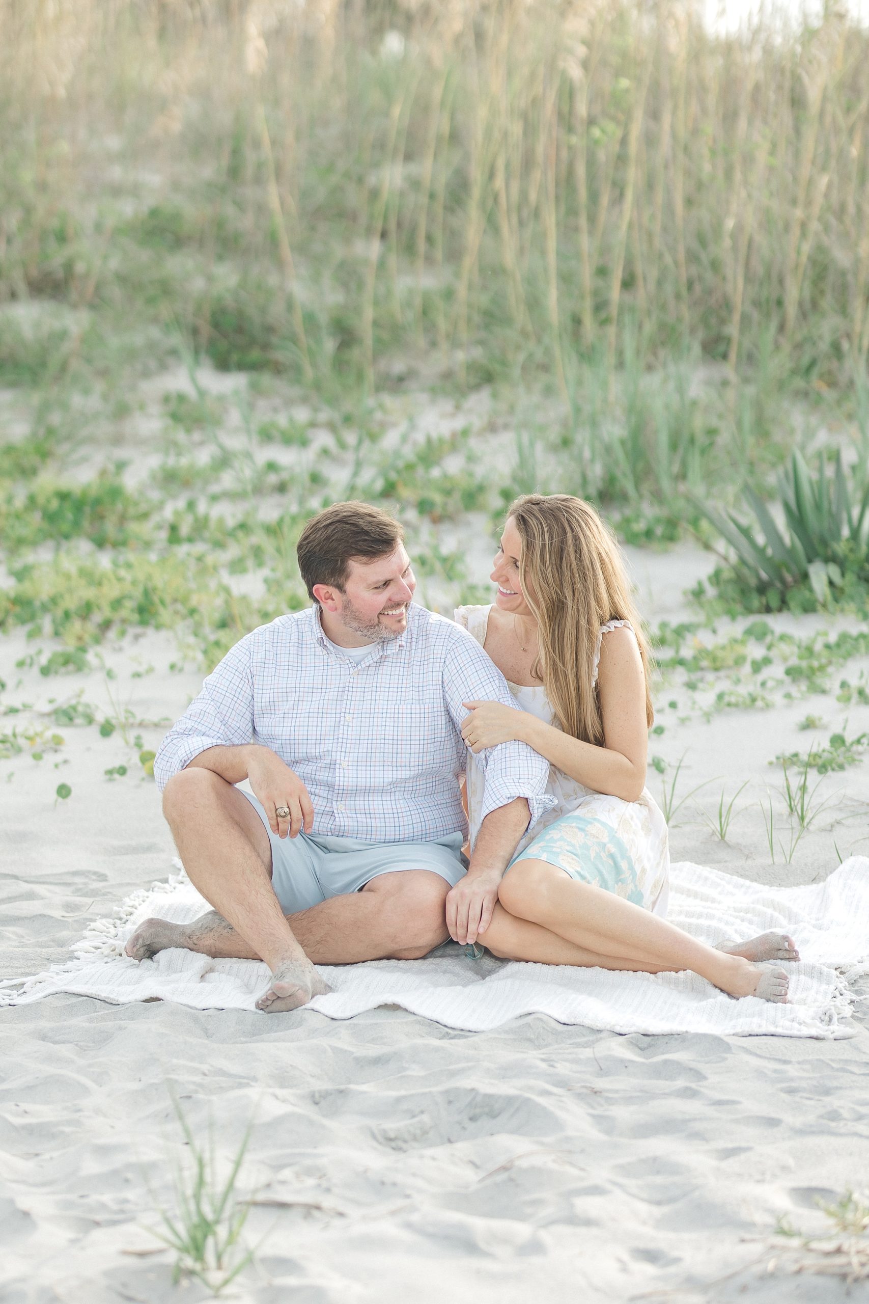 couple sit on blanket on sandy beach