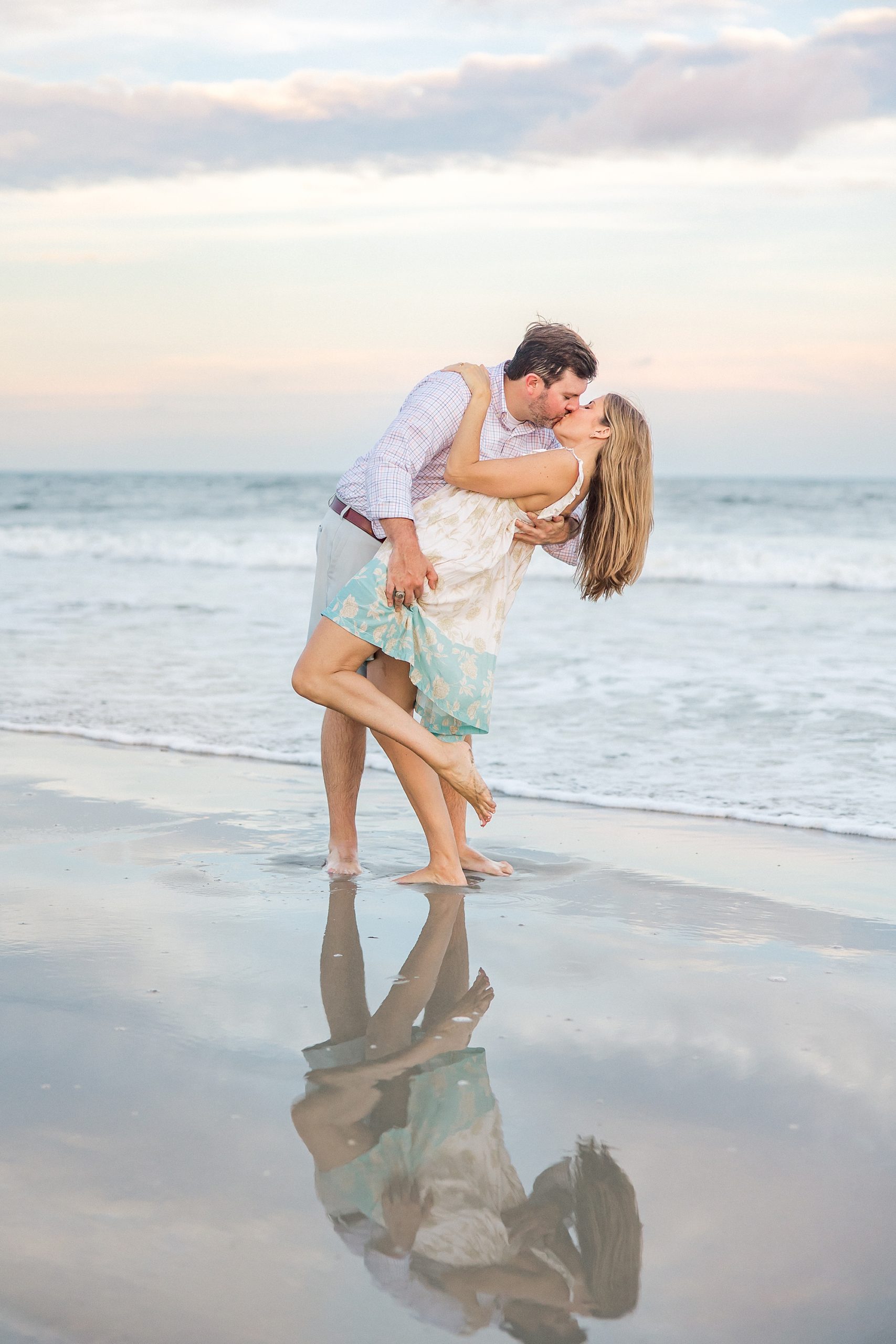 man kisses his fiance on the beach during engagement session