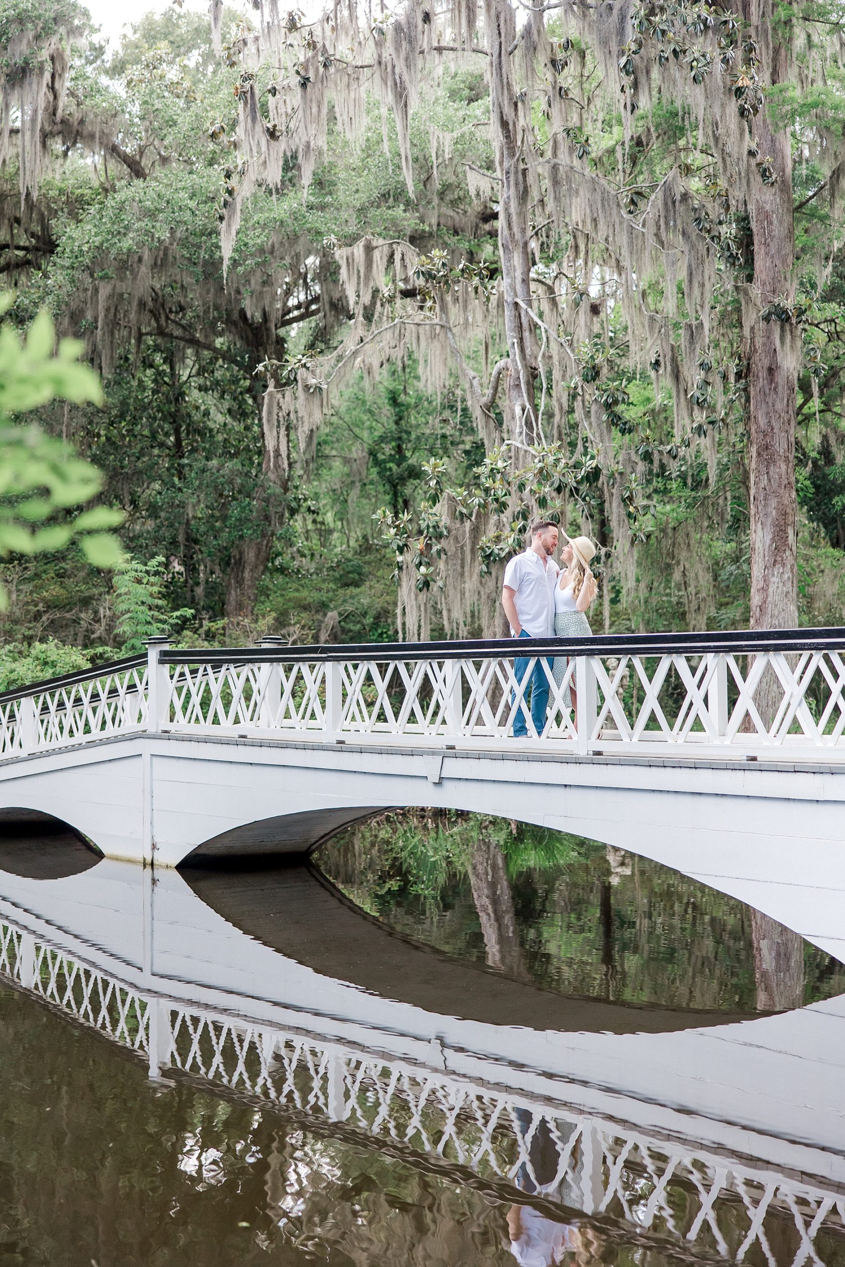 couple walk along the middle of a white bridge at Magnolia Plantation and Gardens