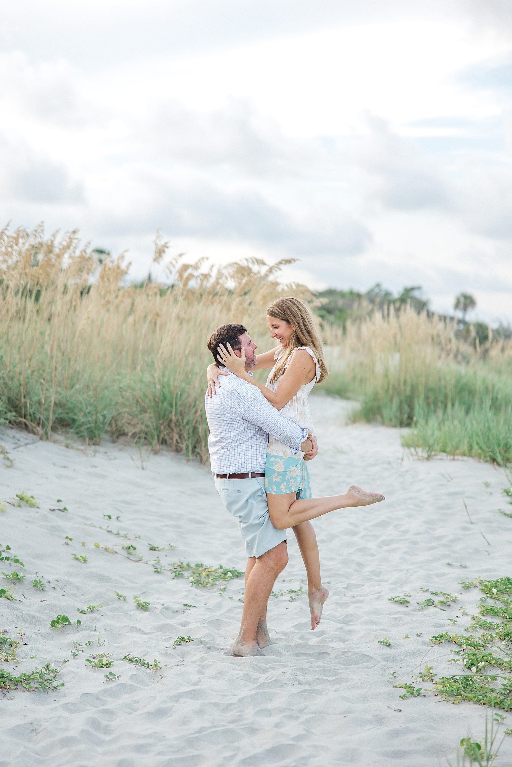 man lifts his fiance up during engagement portraits