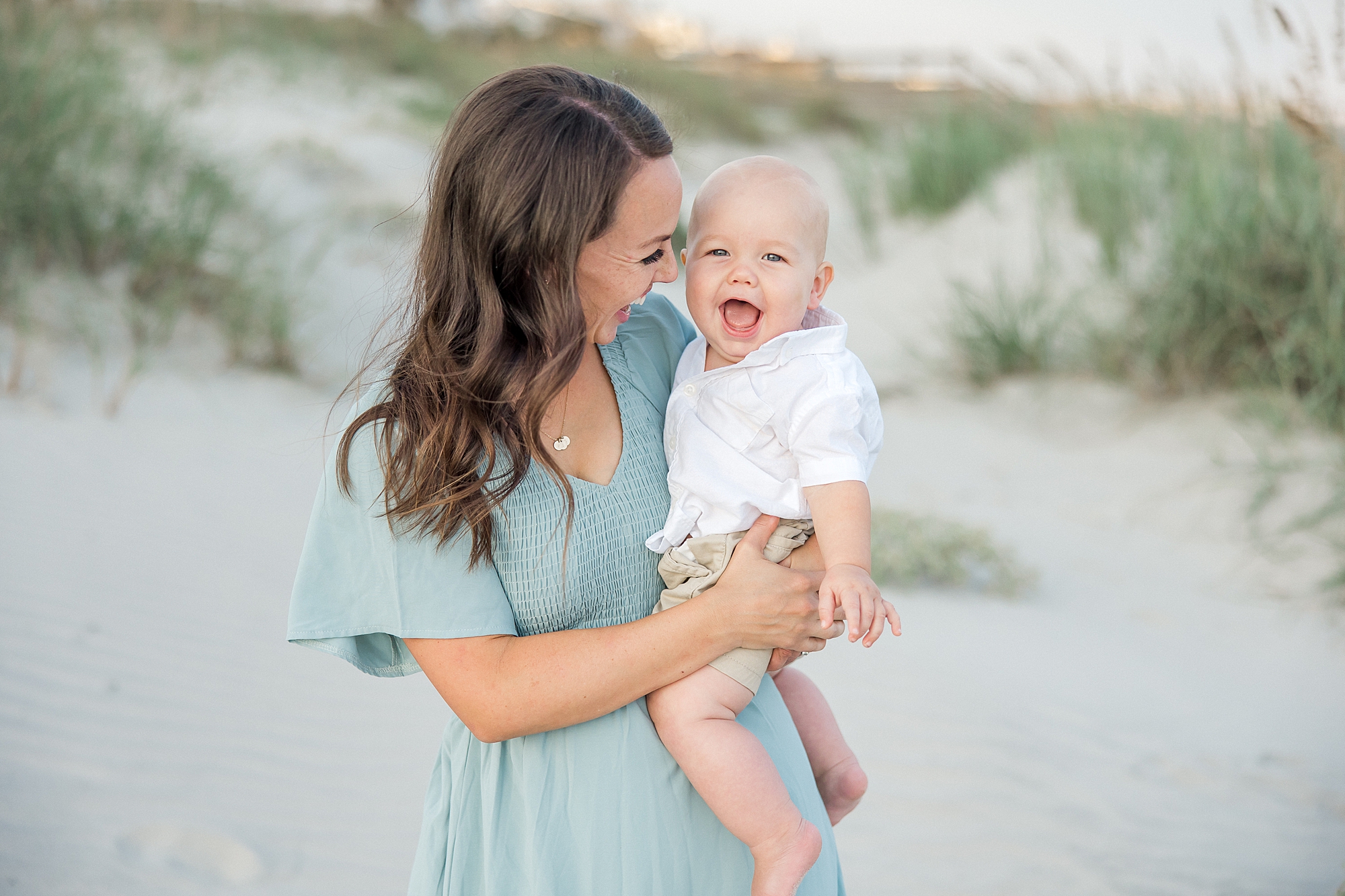baby laughs as his mom holds him during Beach Family portraits