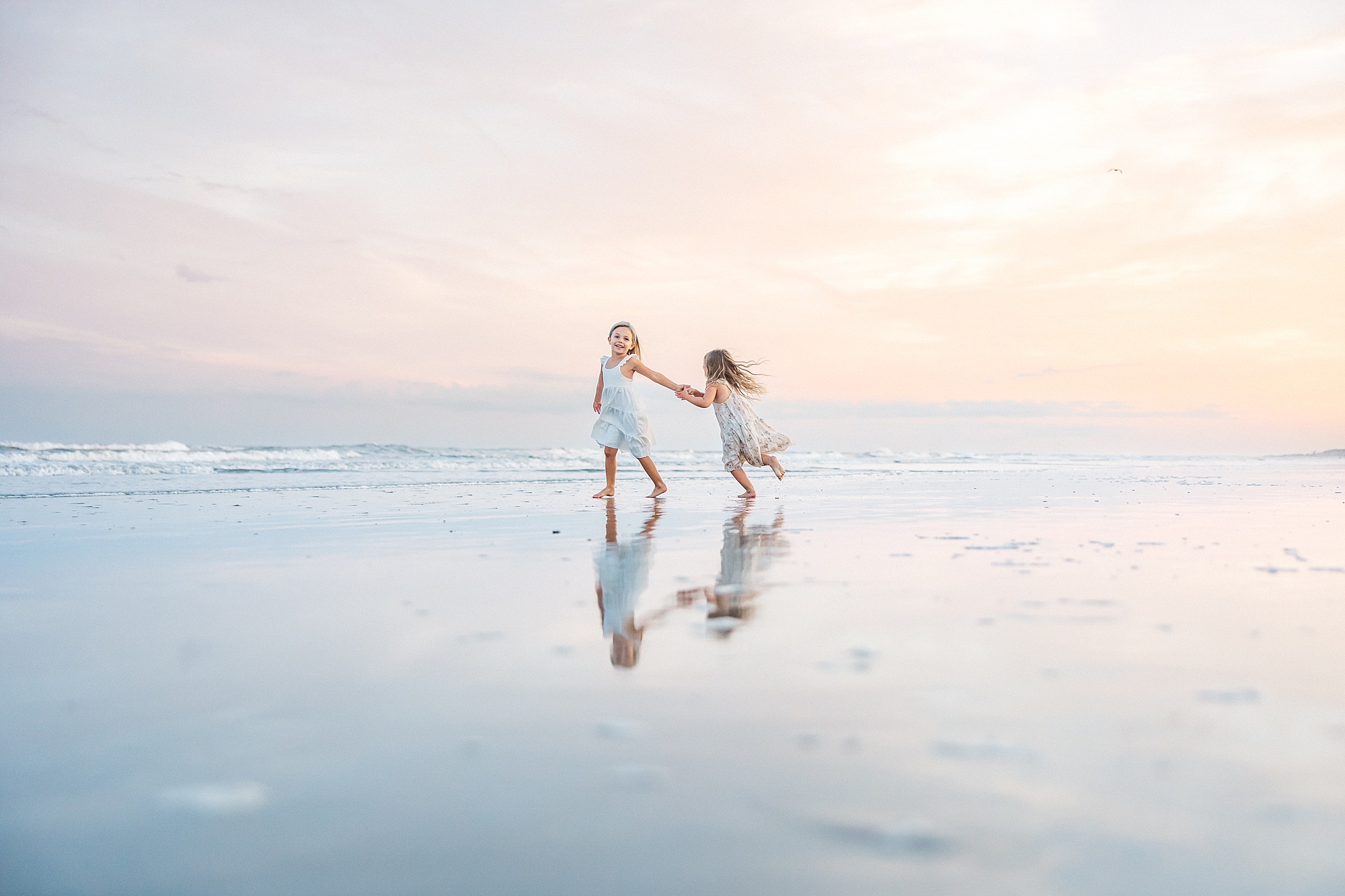 two sisters splash in the ocean during Beach Family Session at Isle of Palms