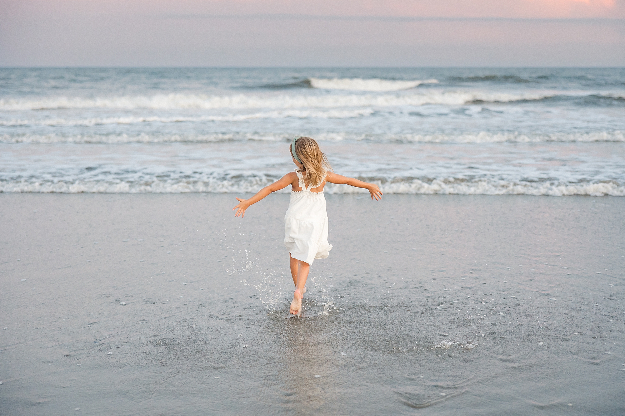 candid portraits of little girl running around on beach