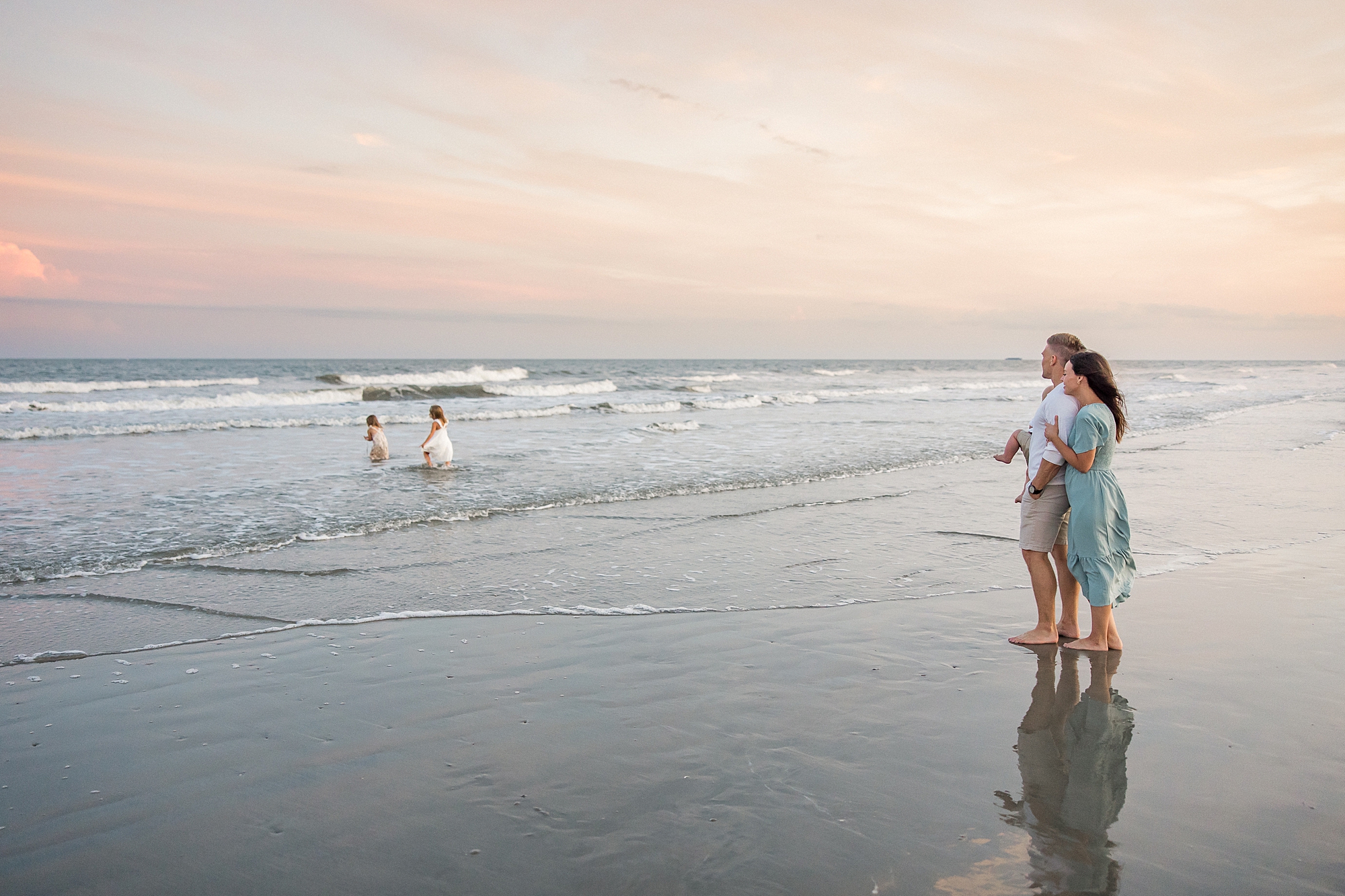 parents watch their girls play in the water during Beach Family Session at Isle of Palms