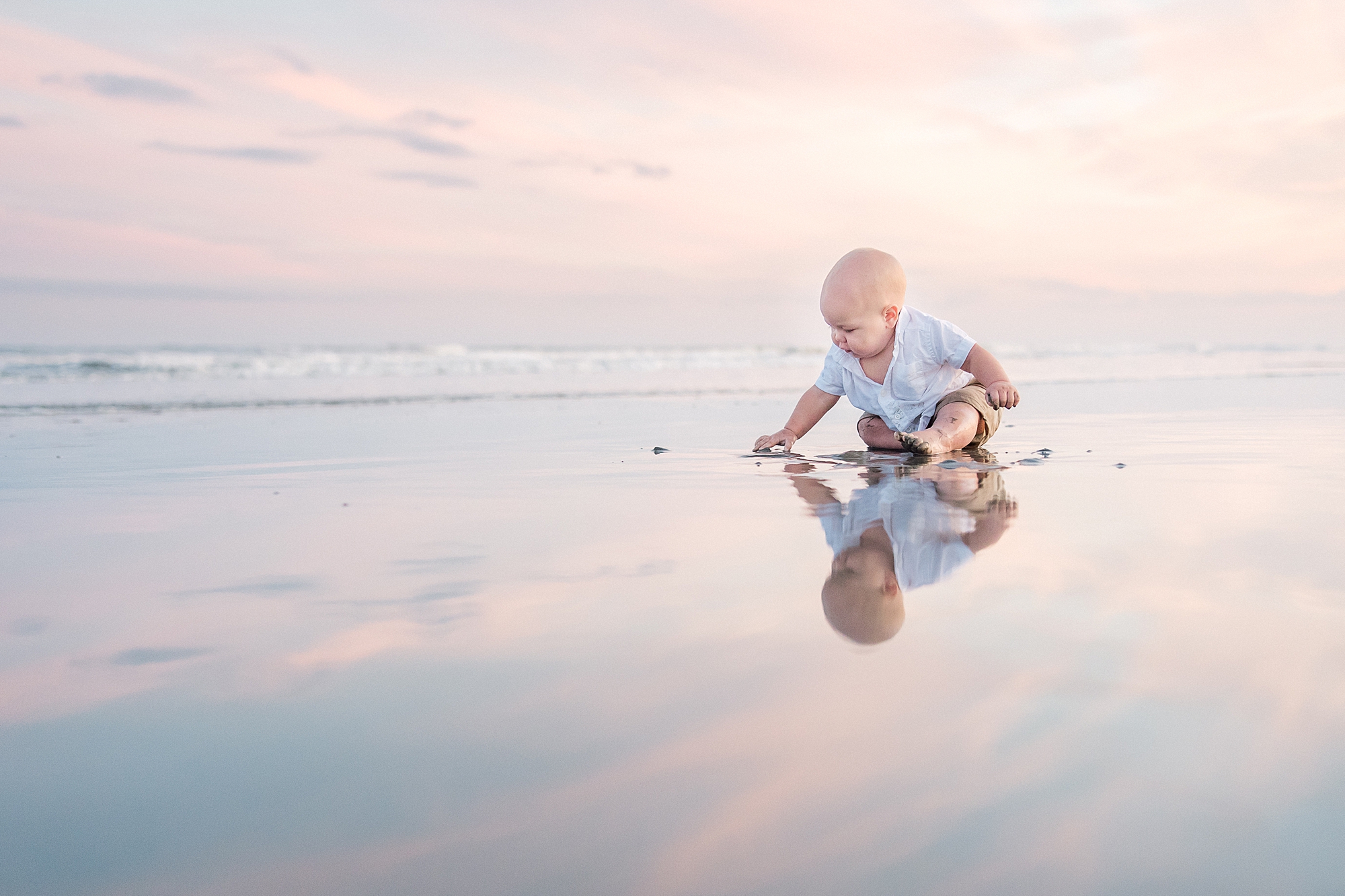 little boy explores the sand and water during beach family session
