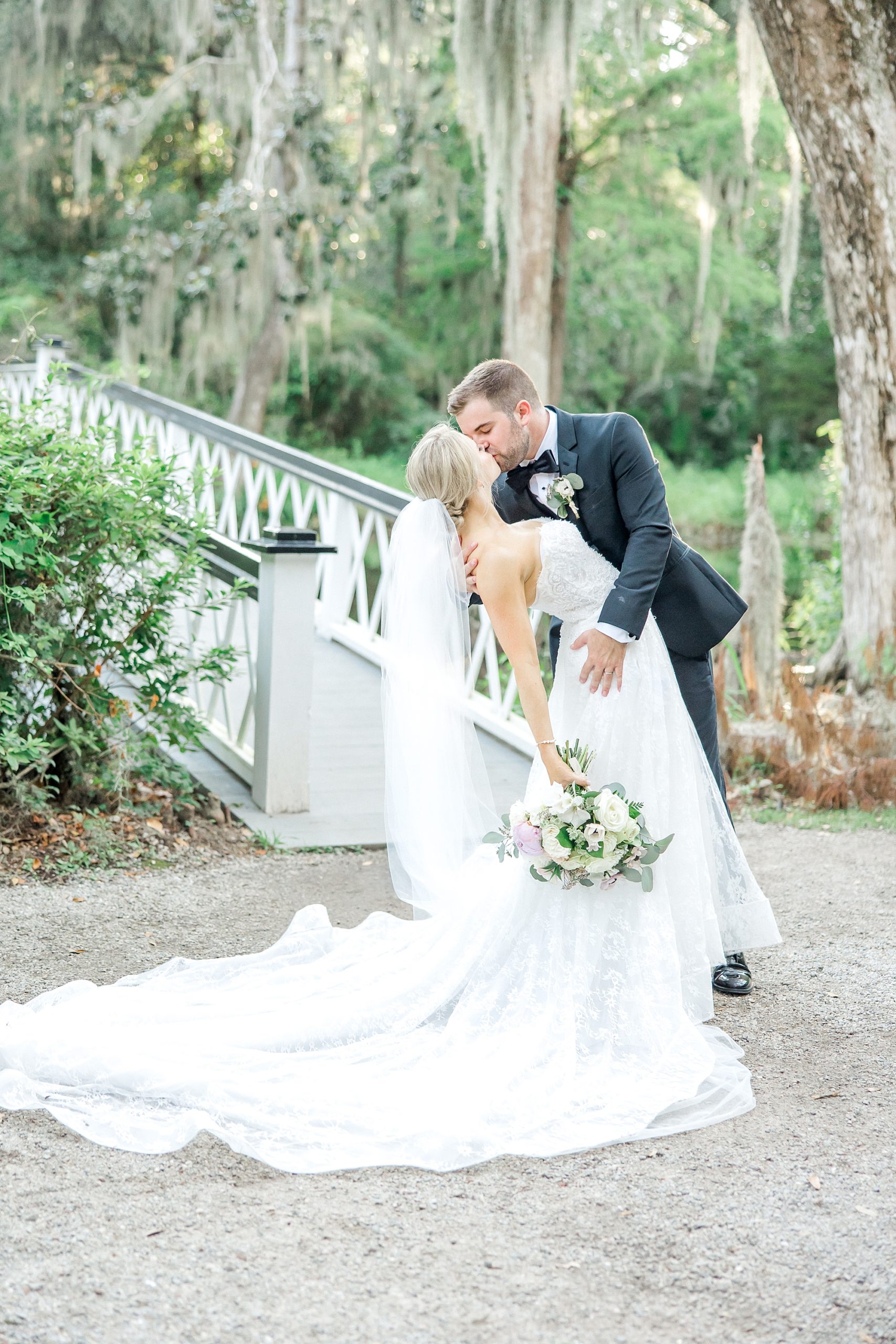 newlyweds kiss by white bridge at Magnolia Plantation and Gardens