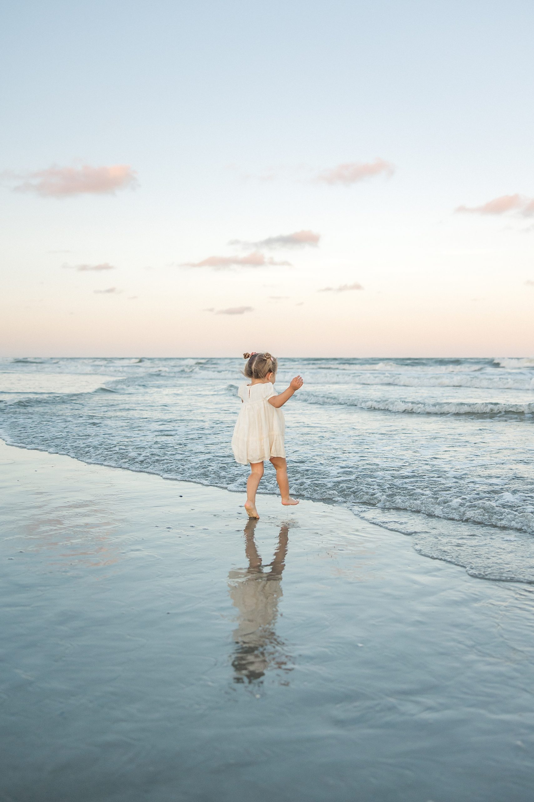 little girl plays at the ocean during Isle of Palms Sunset Family Portraits
