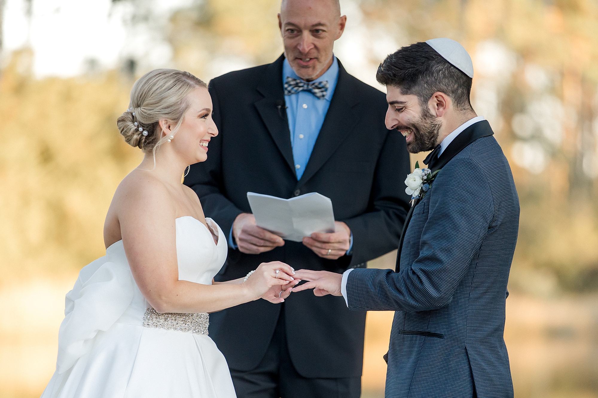 couple exchange rings during outdoor wedding ceremony