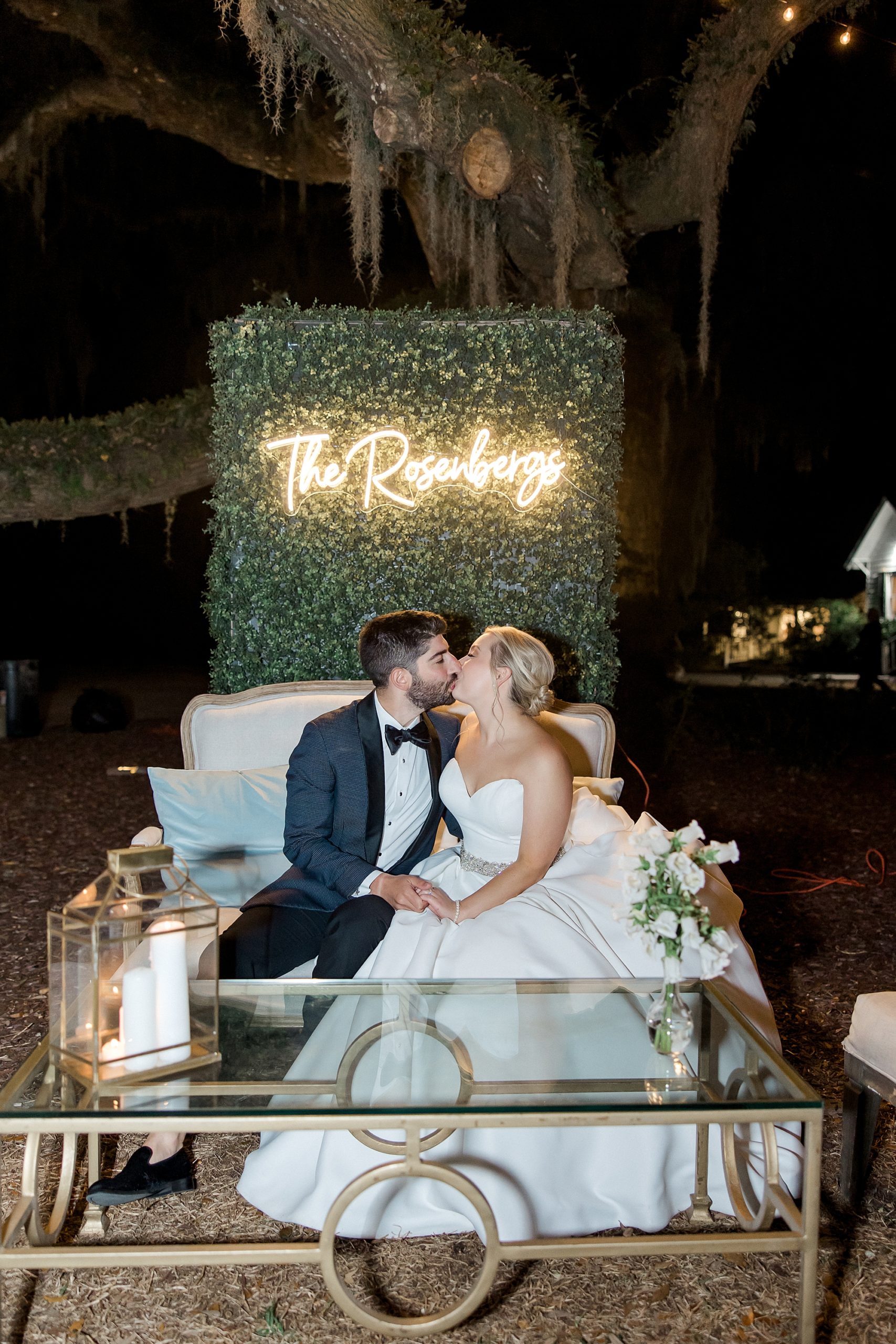 newlyweds kiss by neon wedding sign