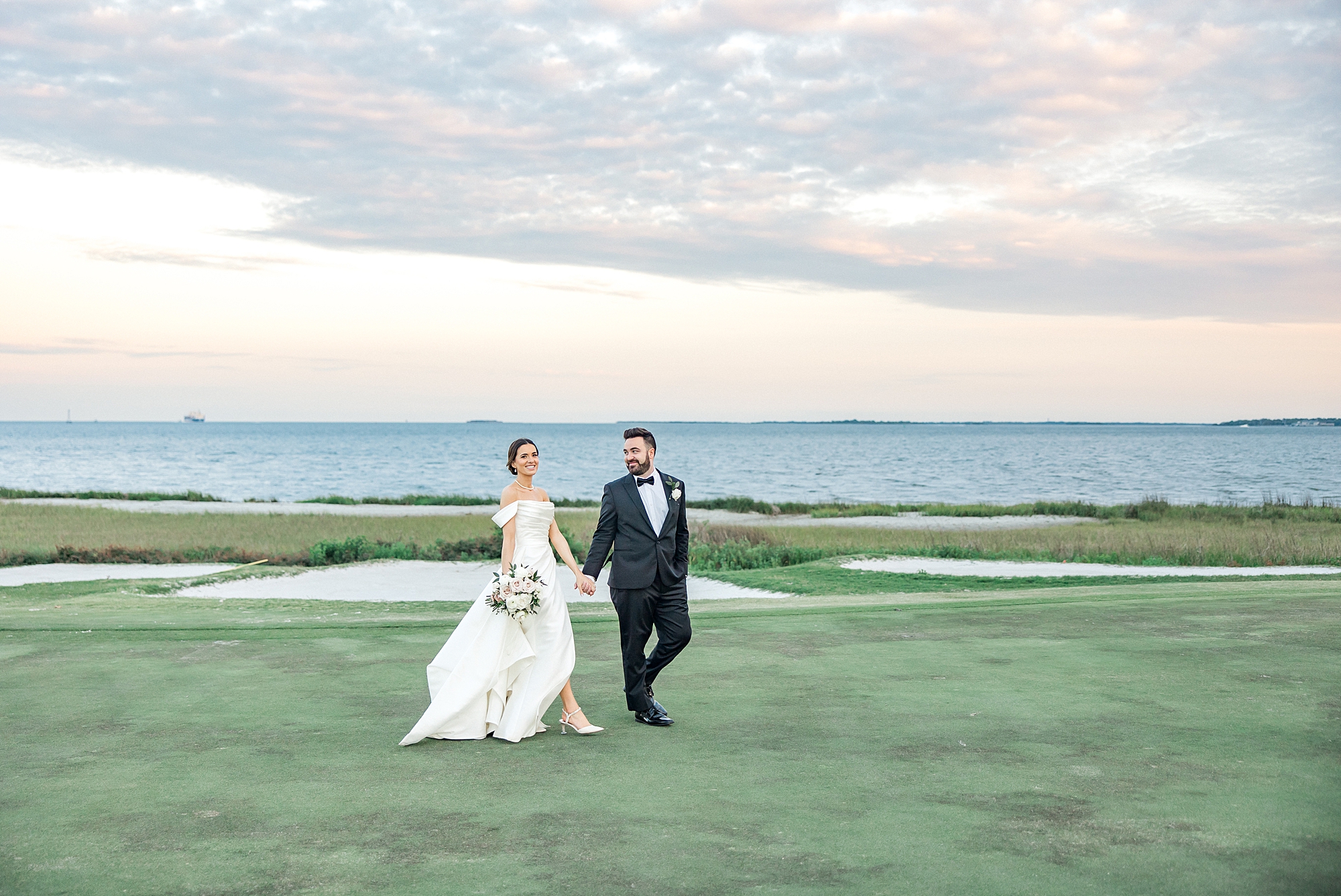 couple walk by the water during newlywed portraits