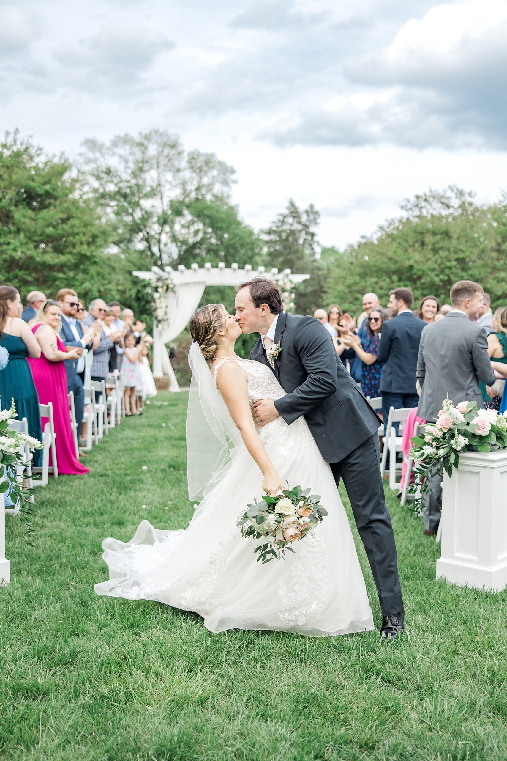 newlyweds kiss at the end wedding aisle