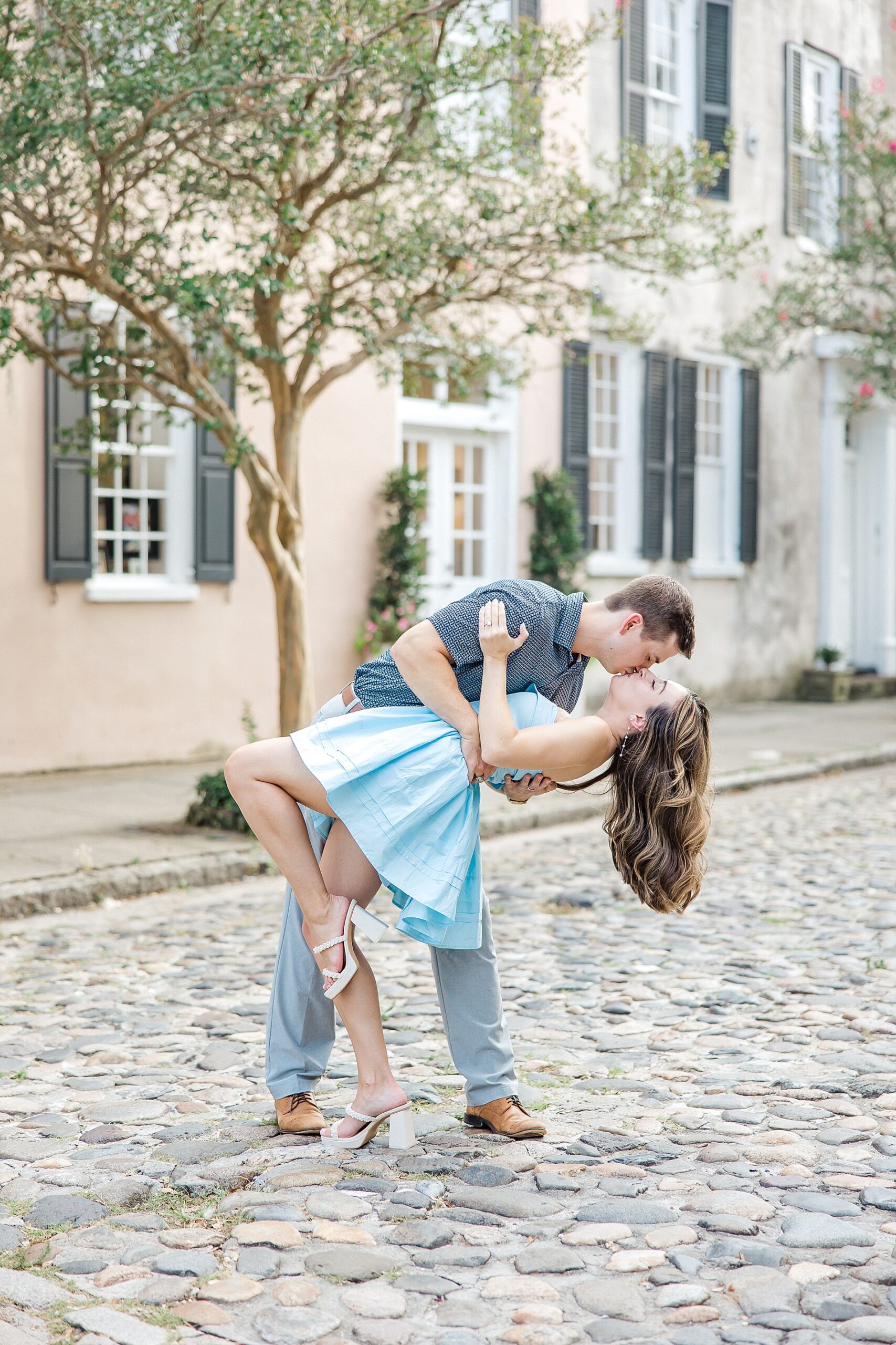 engaged couple kiss in the middle of cobblestone street