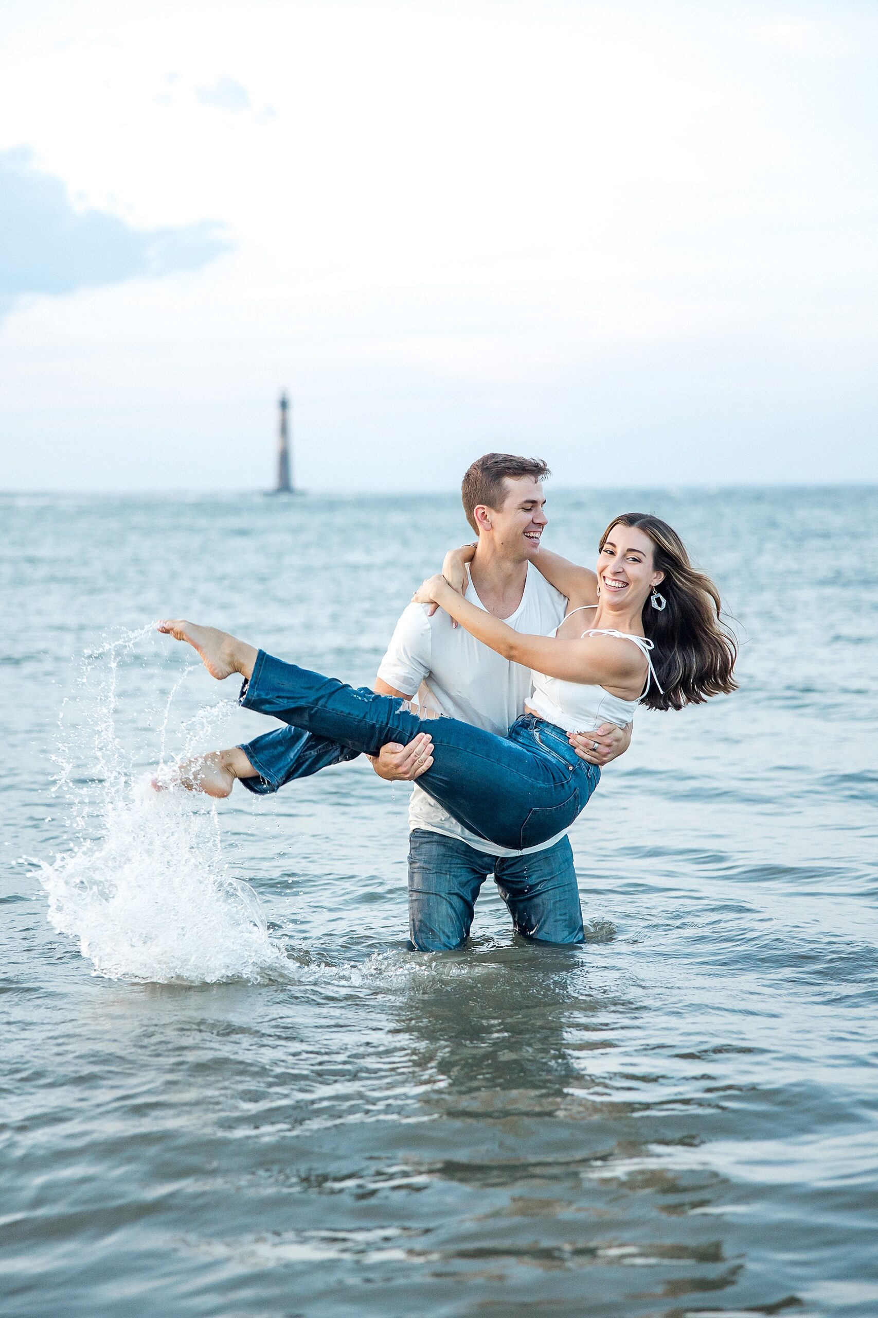 couple splash in the ocean during romantic Folly Beach Engagement session