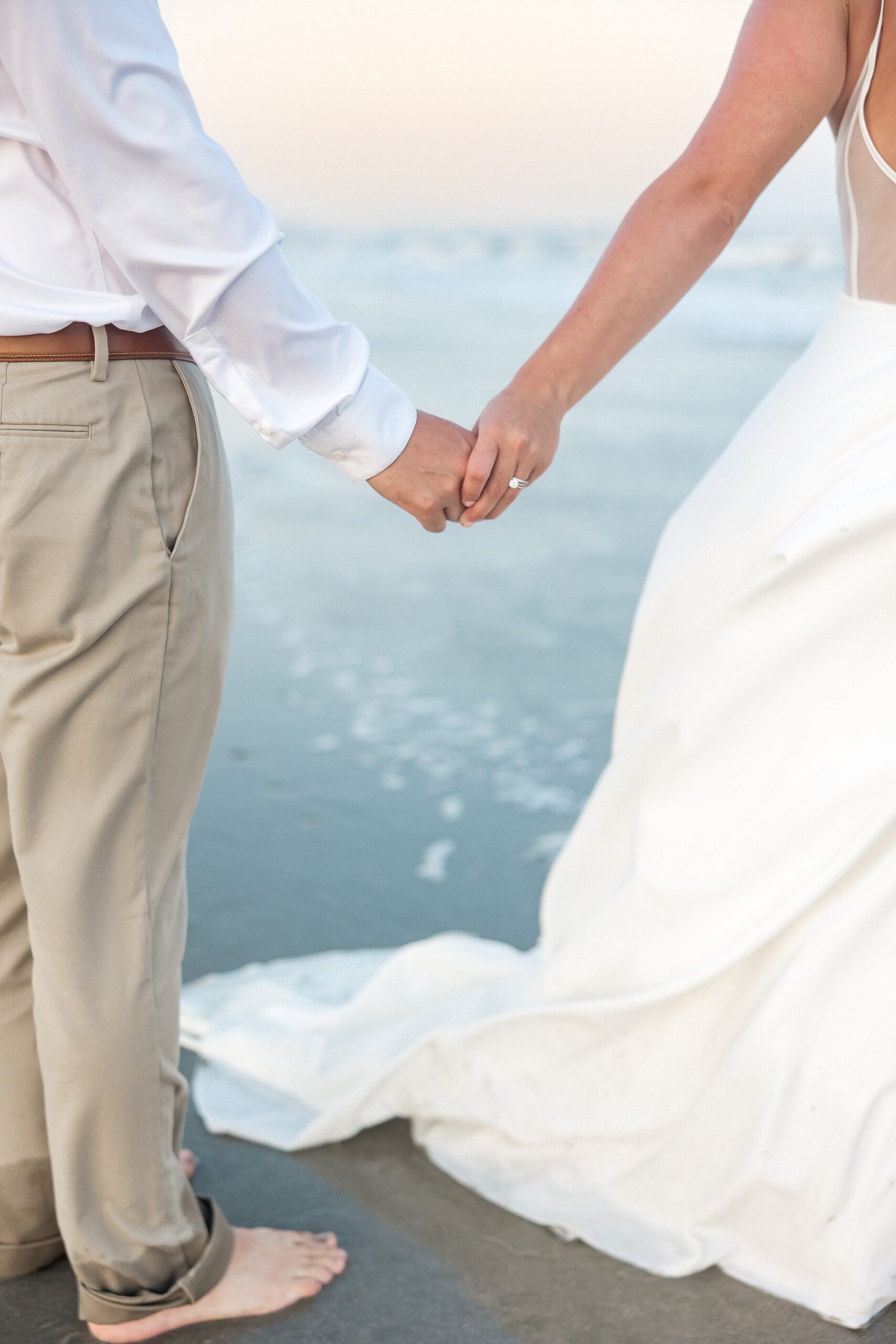 couple hold hands on the beach