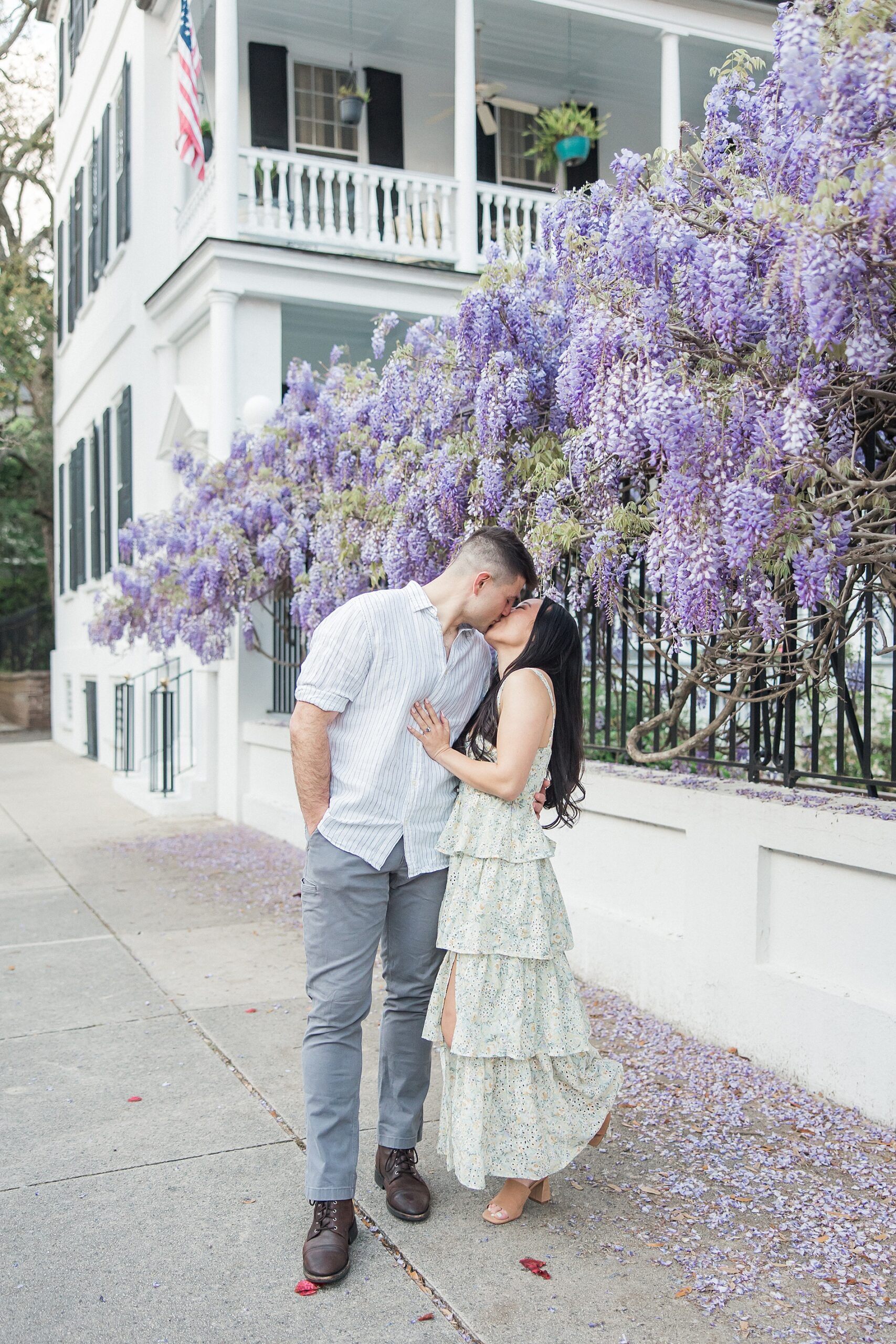 couple kiss under lilac wisterias