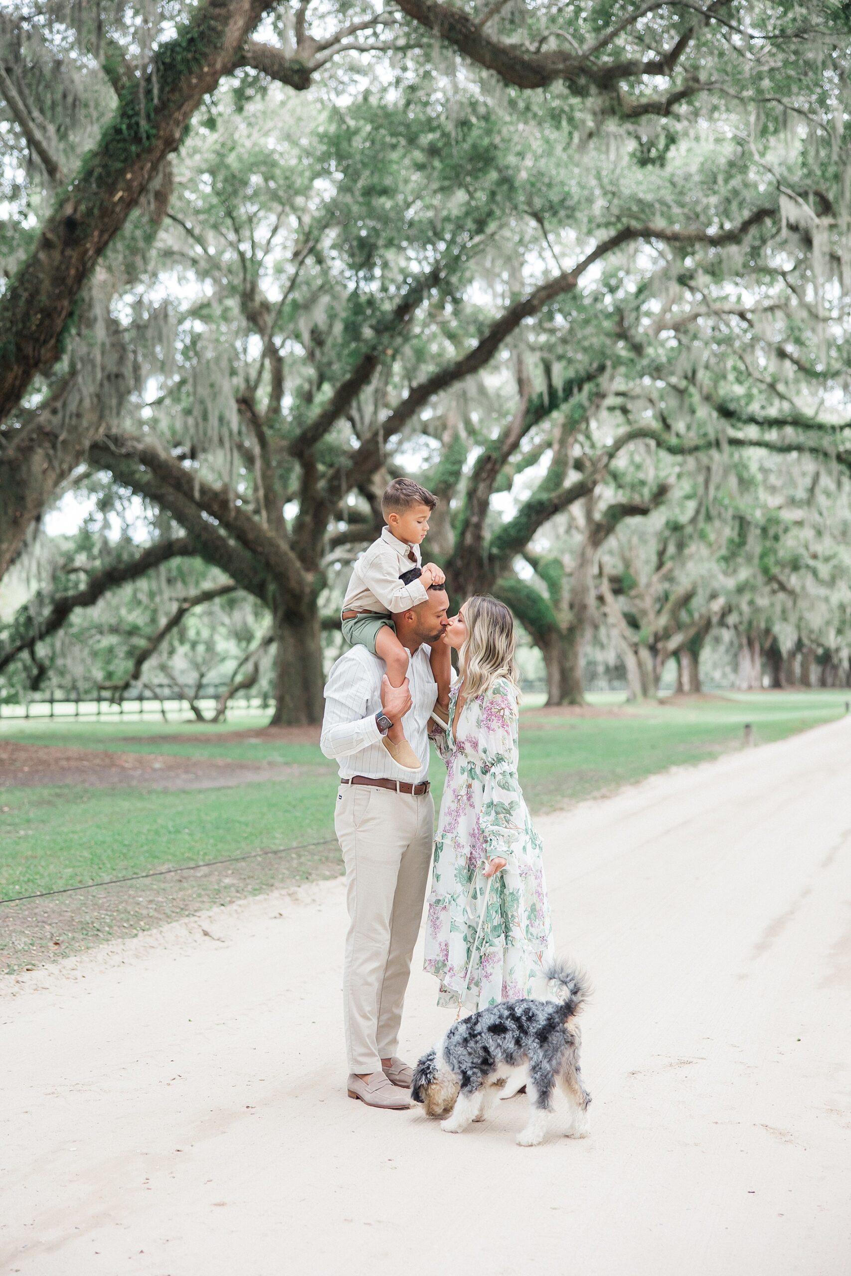 parents kiss with son on shoulders