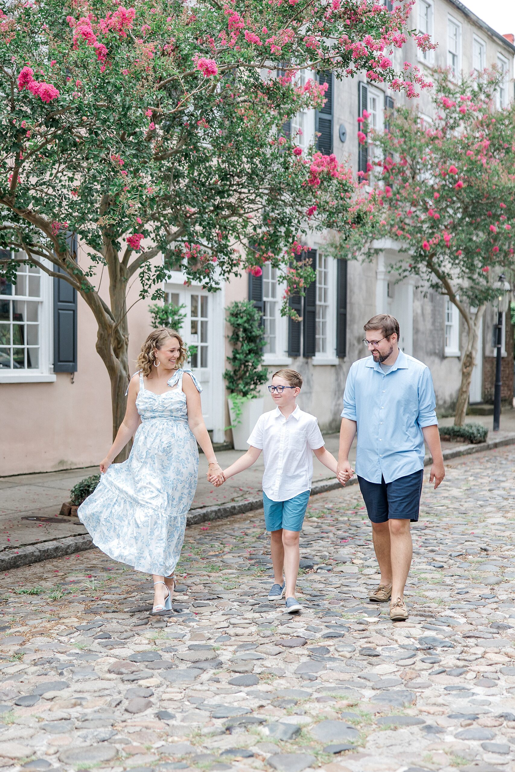 family of three walks together holding hands down cobblestone streets