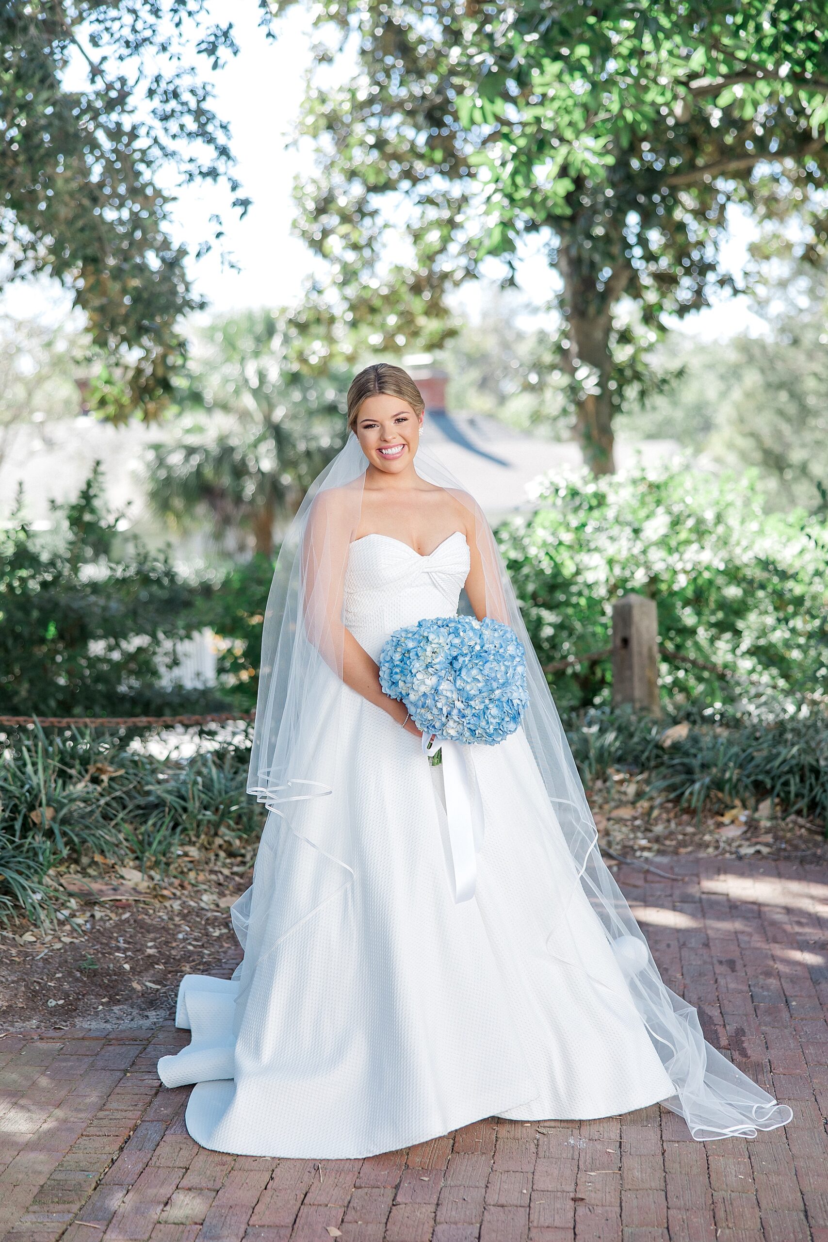 bride poses outside holding blue hydrangea bridal bouquet