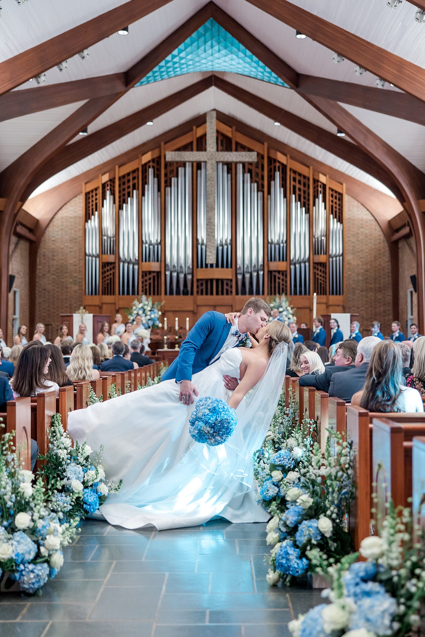 romantic wedding portraits of groom dipping his bride down the aisle