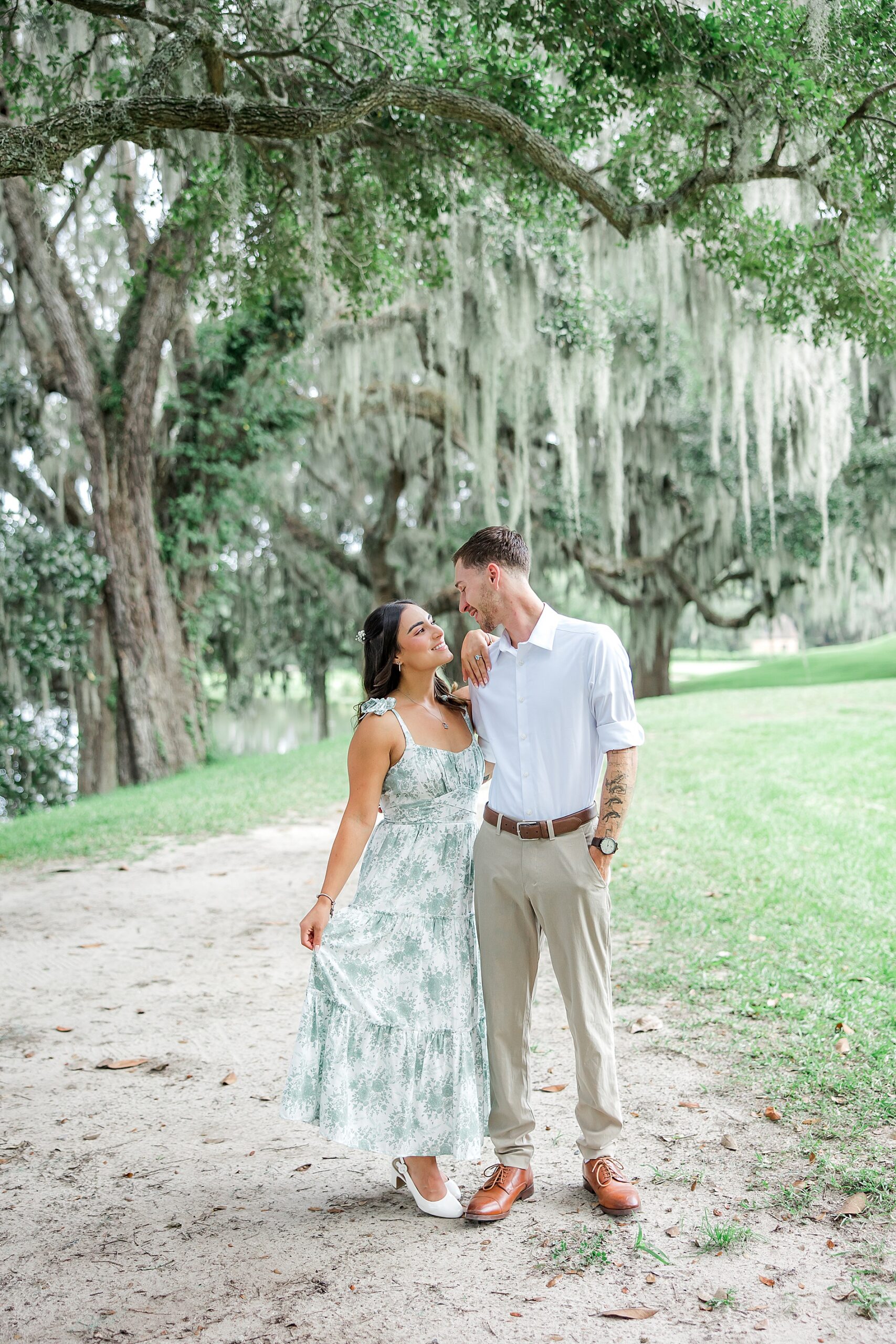 couple standing under oak trees with Spanish moss hanging down